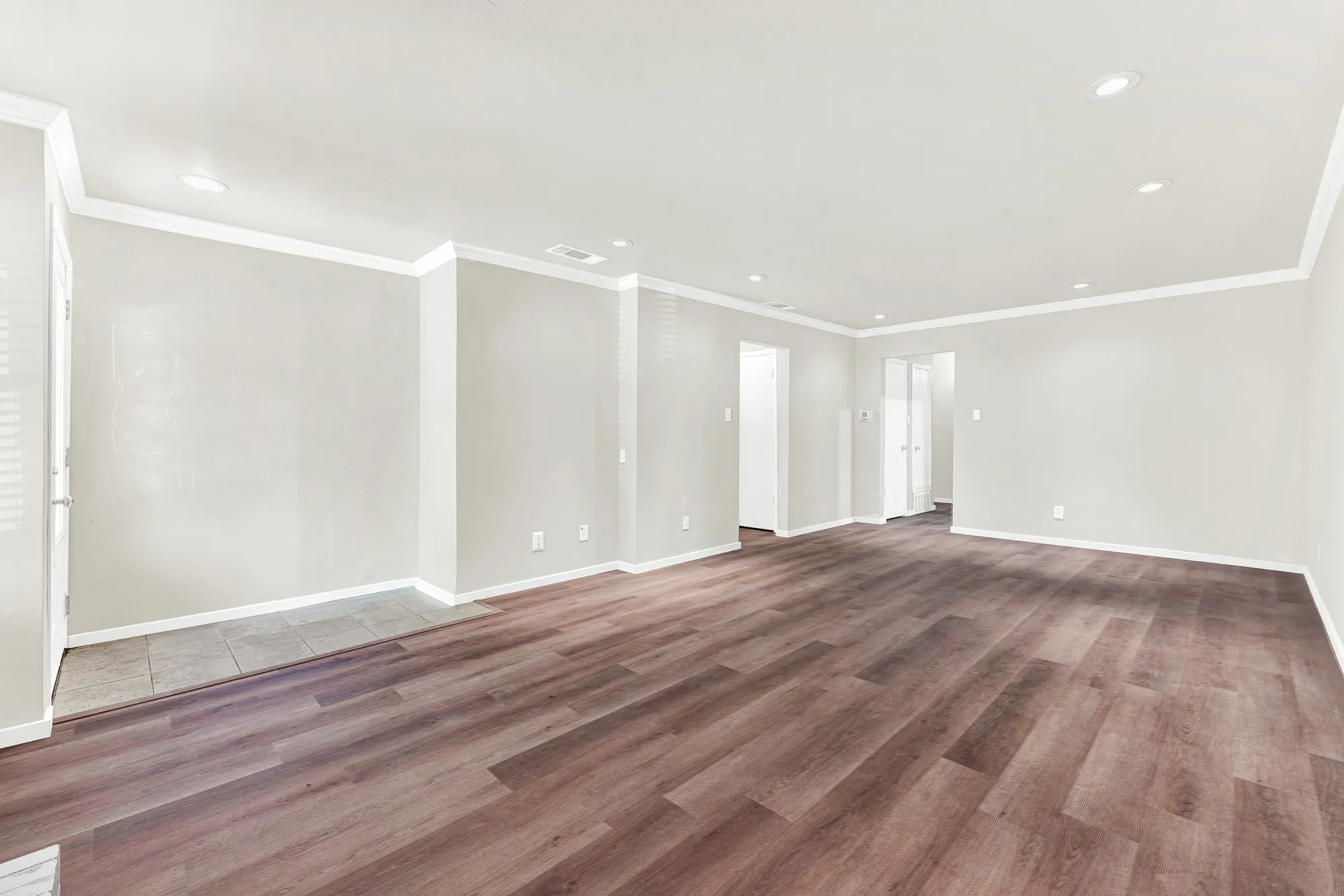 Wood-finish flooring throughout, recessed ceiling lighting, crown molding, and neutral wall tones