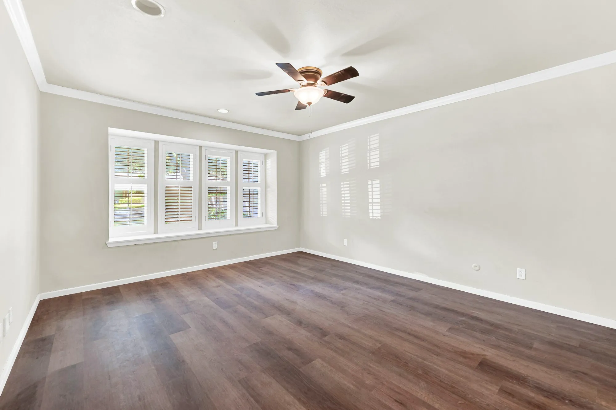 Wood-finish flooring, plantation shutters, crown molding, recessed lighting, and a ceiling fan