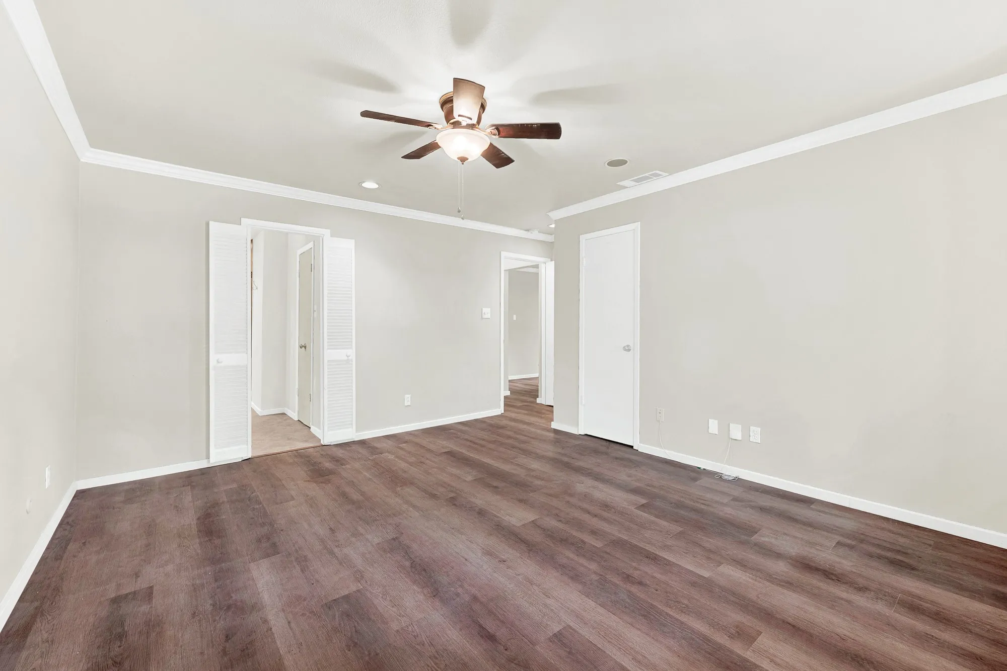 Spacious room featuring wood-finish flooring, light gray walls, white crown molding, a ceiling fan, and recessed lighting