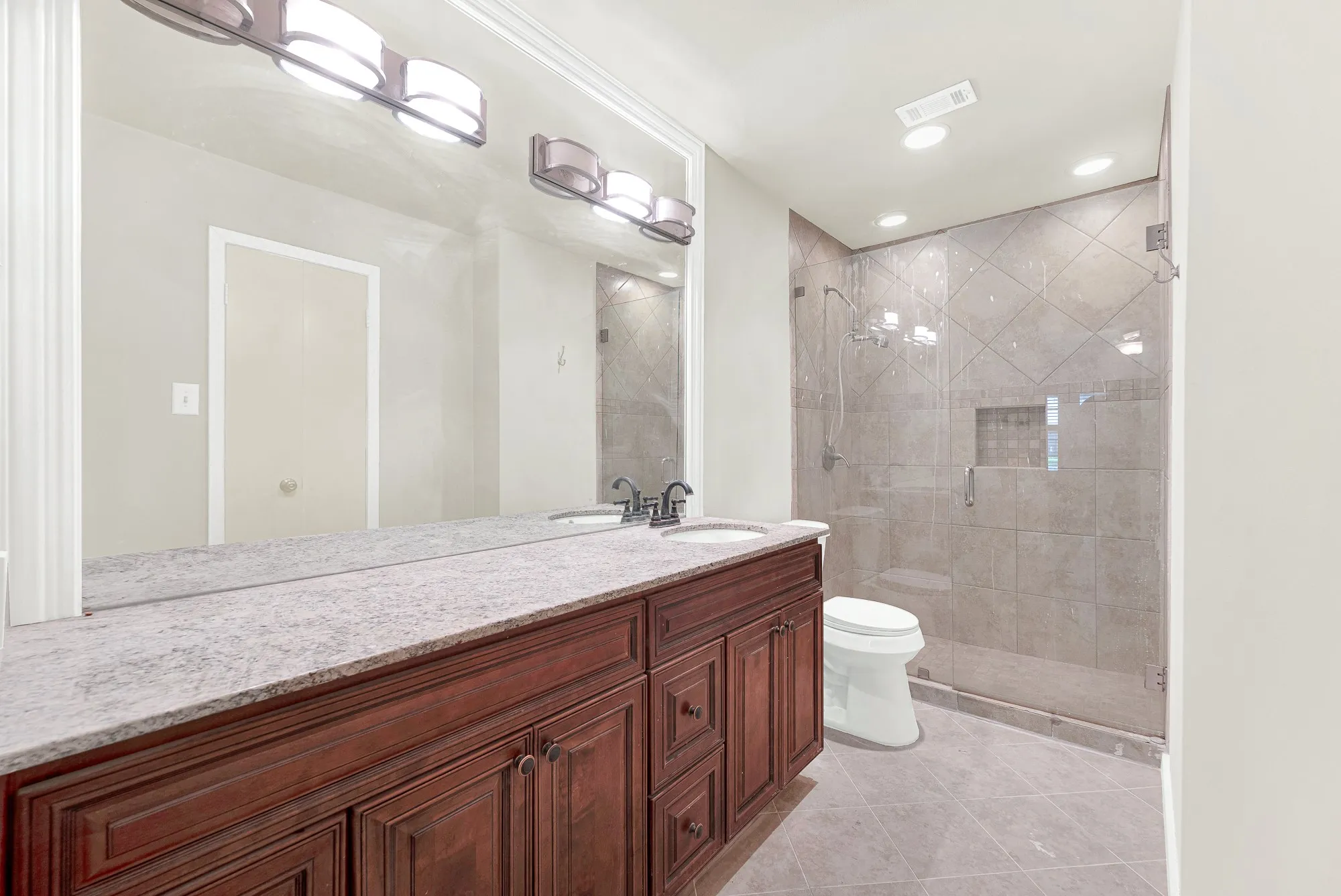 Dual vanity with stone countertop and wood-finish cabinetry