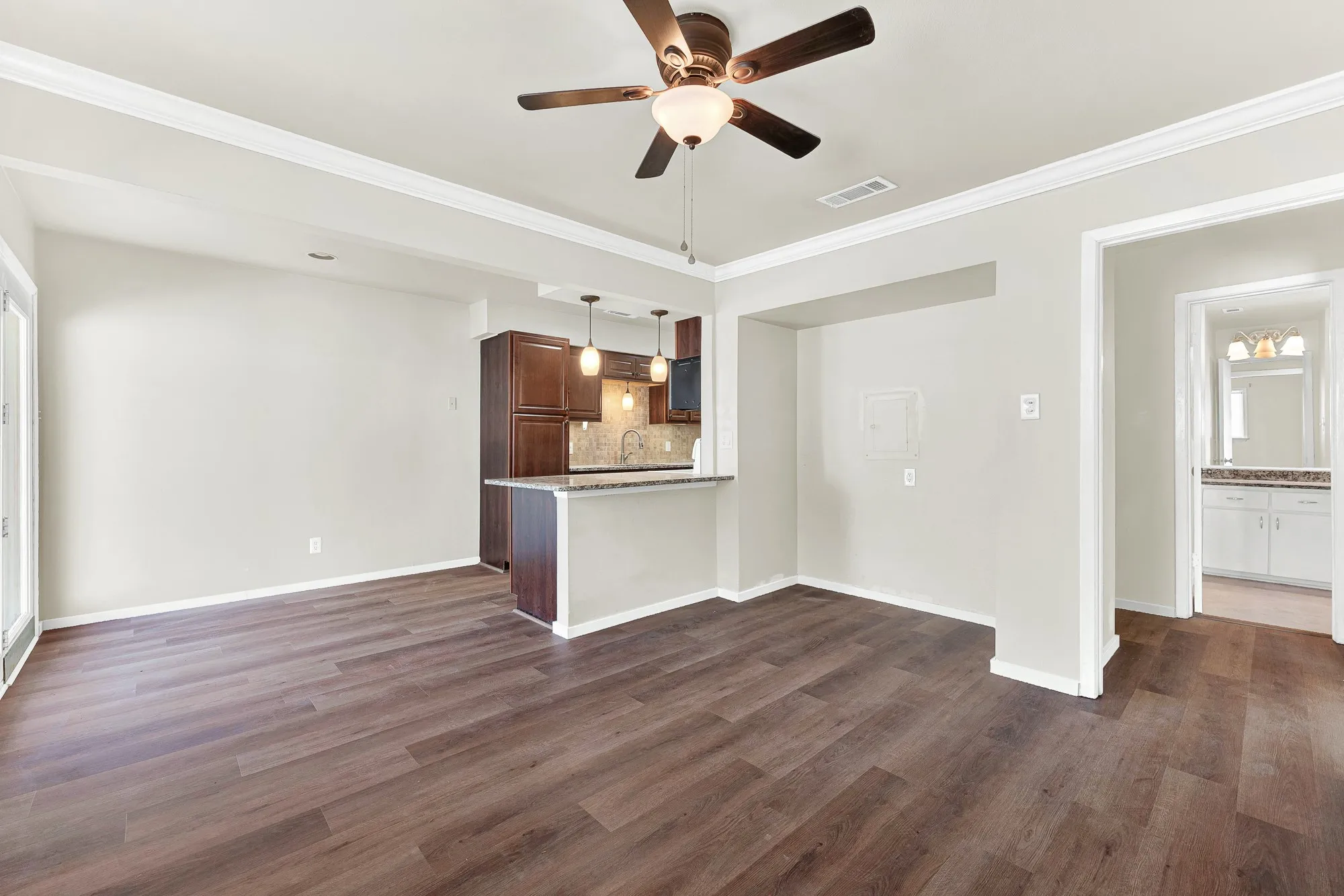 Wood-finish flooring, crown molding, and a ceiling fan with integrated lighting