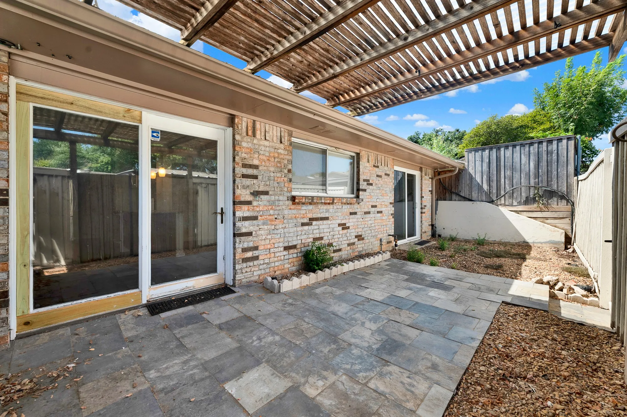 Paved patio area with a slatted wood pergola