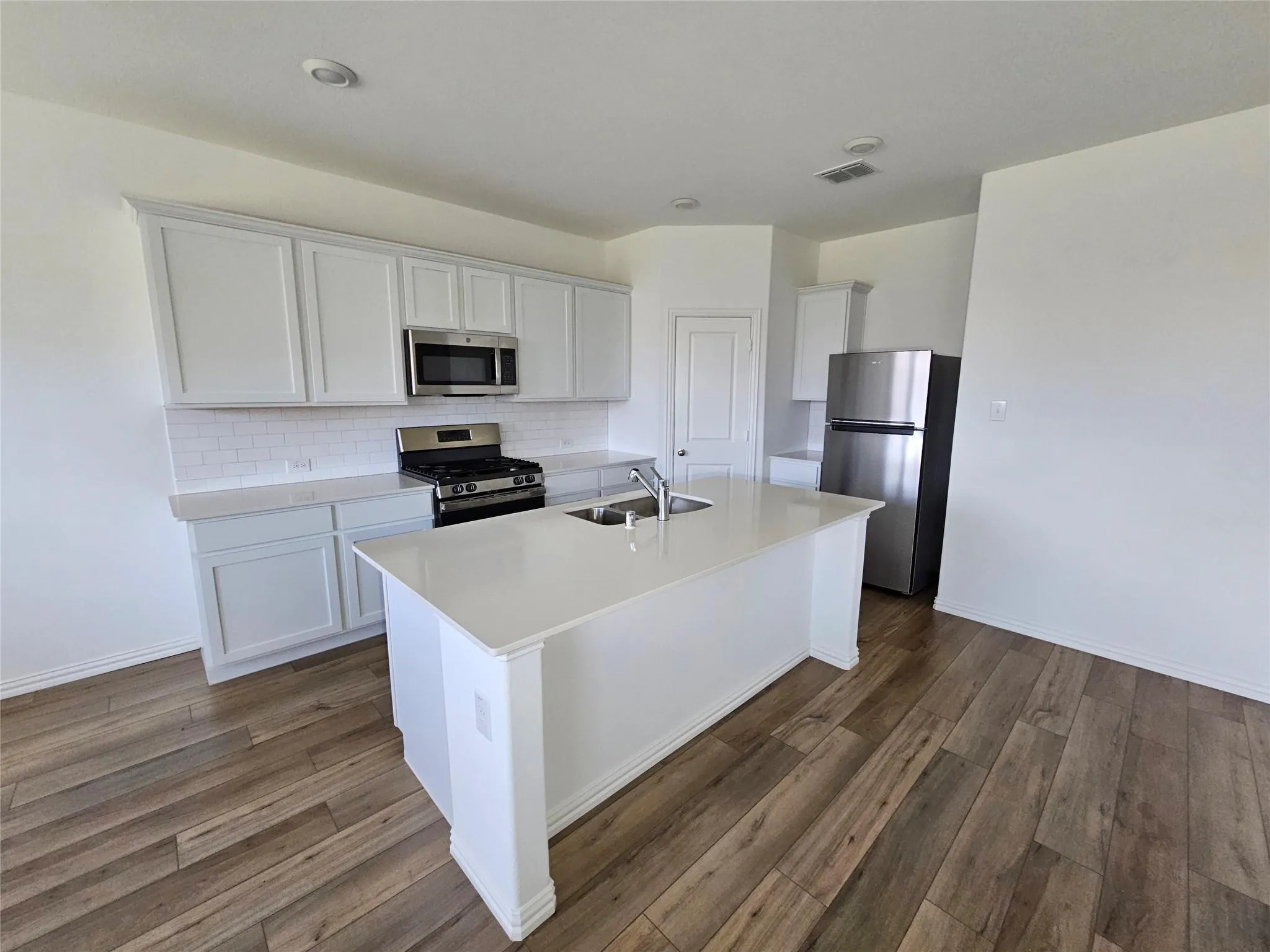 Kitchen featuring white cabinetry, stainless steel appliances, a subway tile backsplash, and wood-finish flooring