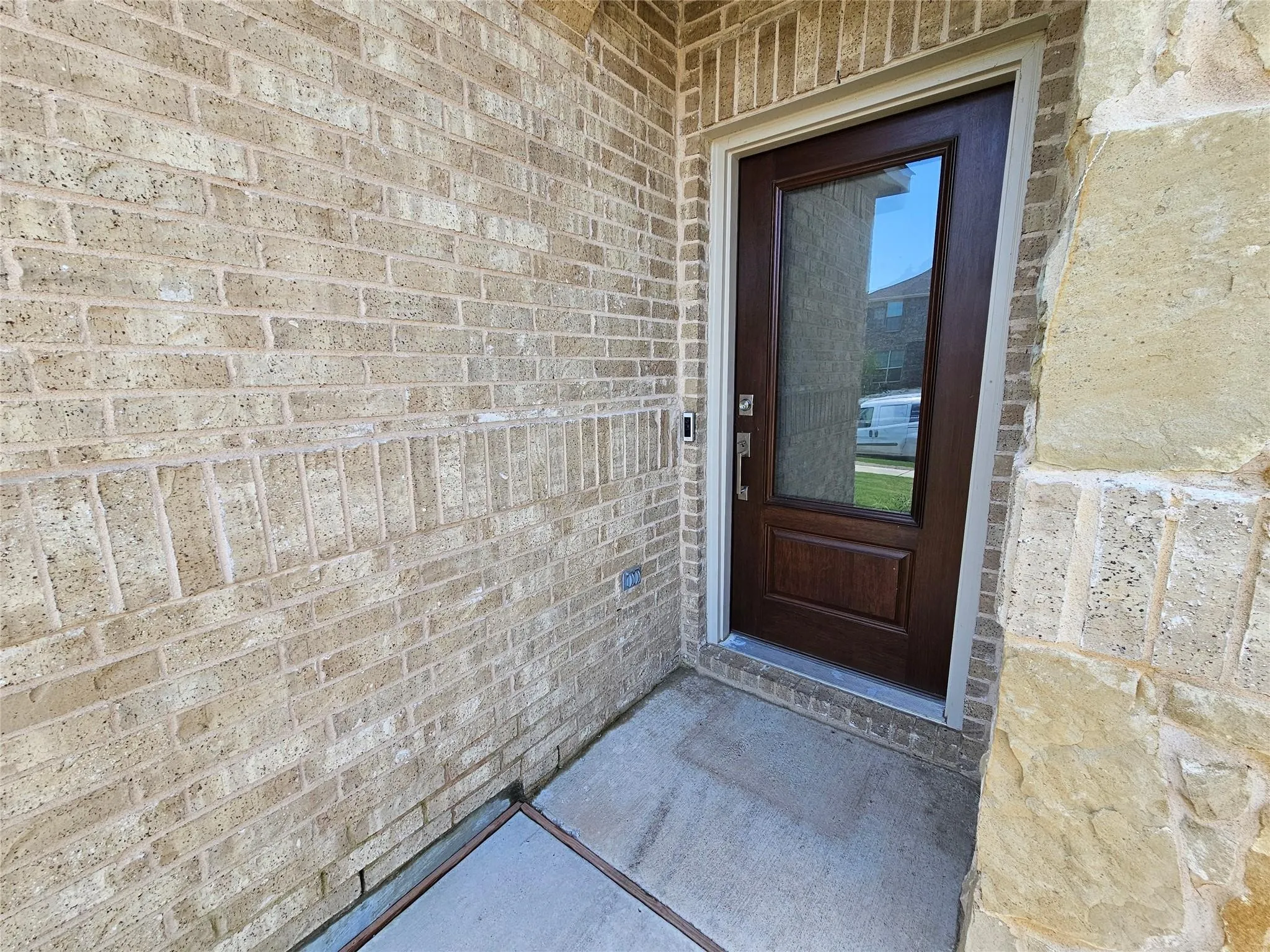 Brick exterior with stone accents and a wood-panel entry door featuring a glass insert