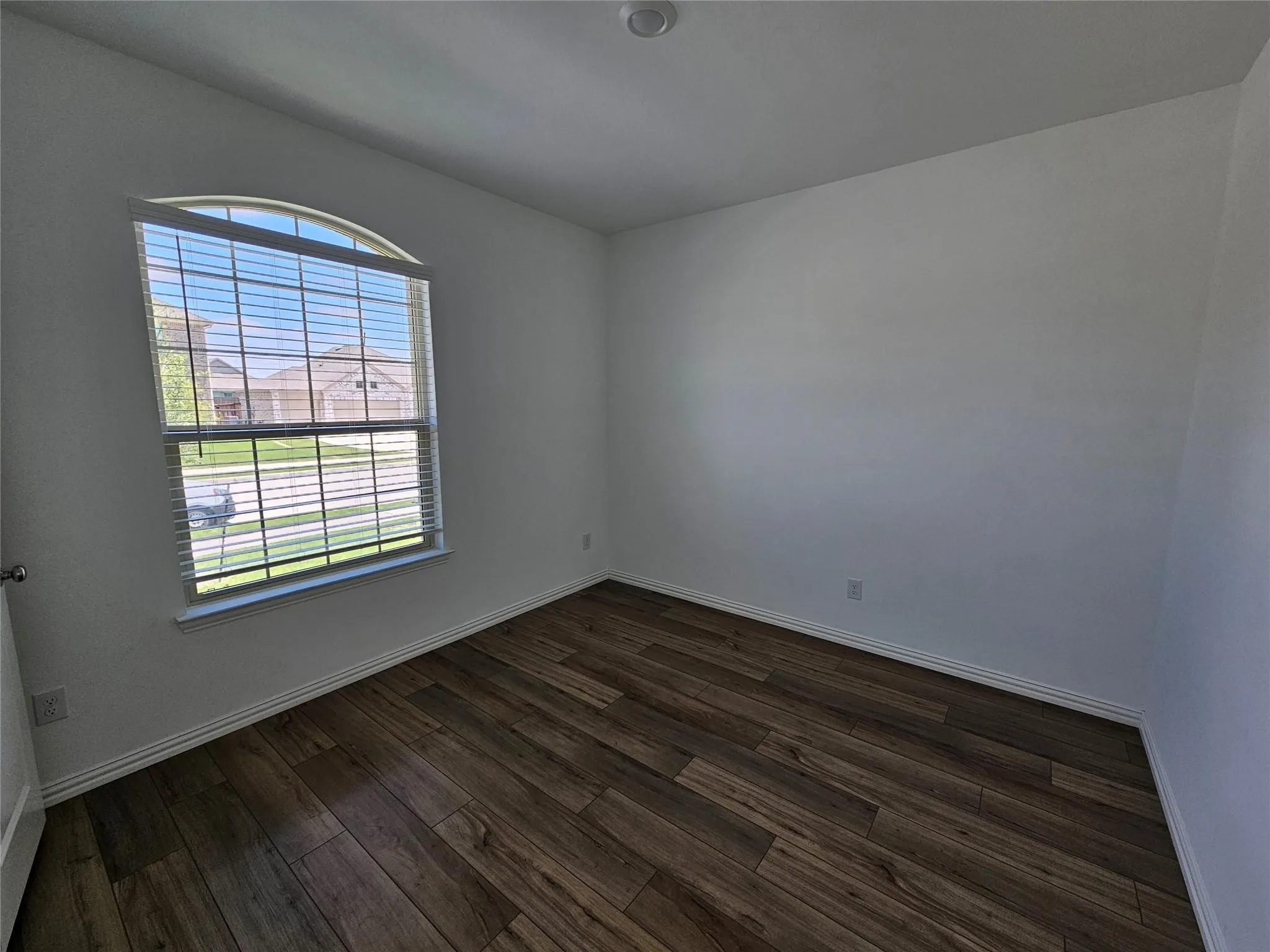 Arched window with blinds, wood-finish flooring, and recessed lighting