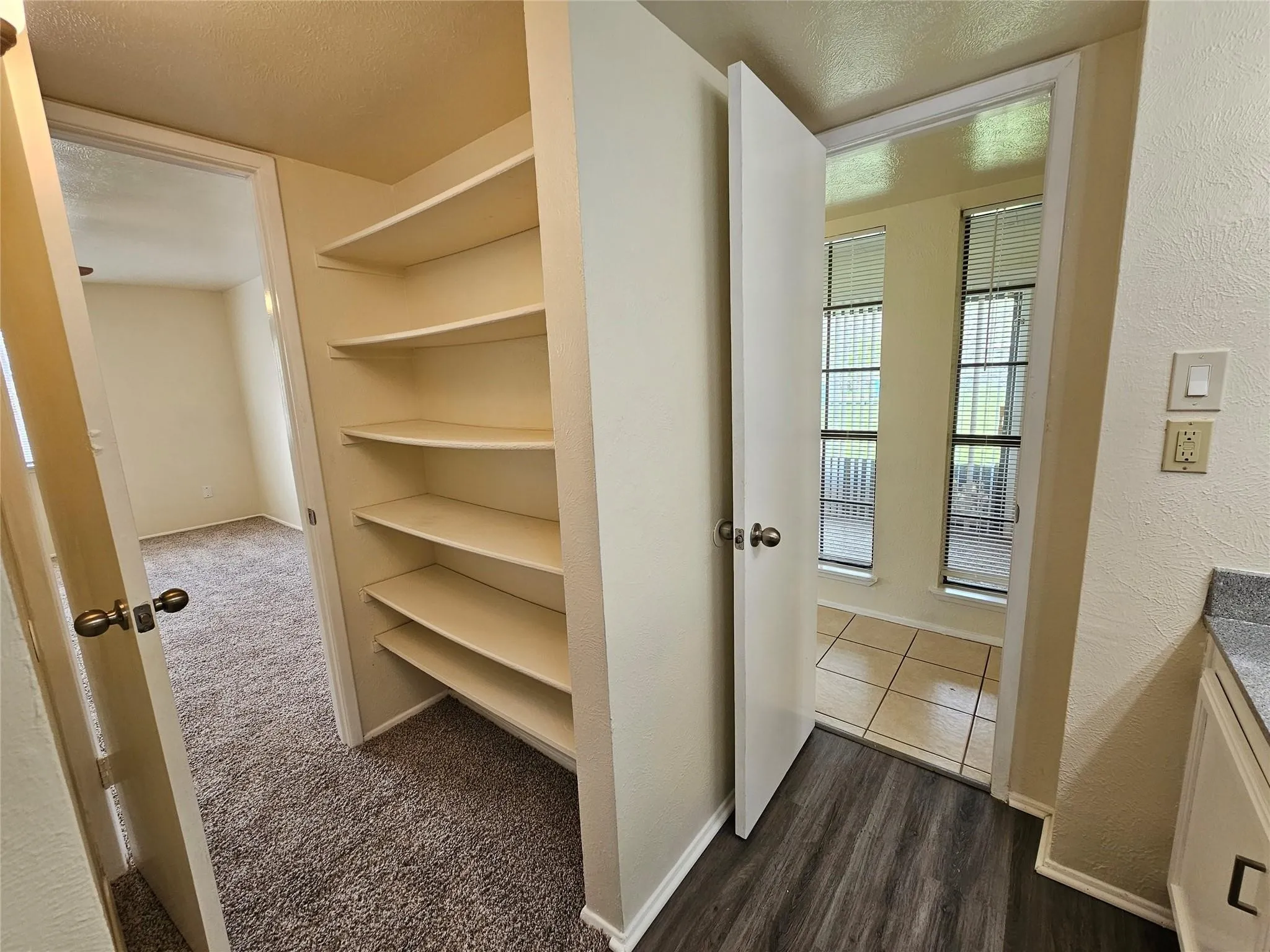 Built-in shelving, wood-finish flooring, textured walls, and a light-colored countertop