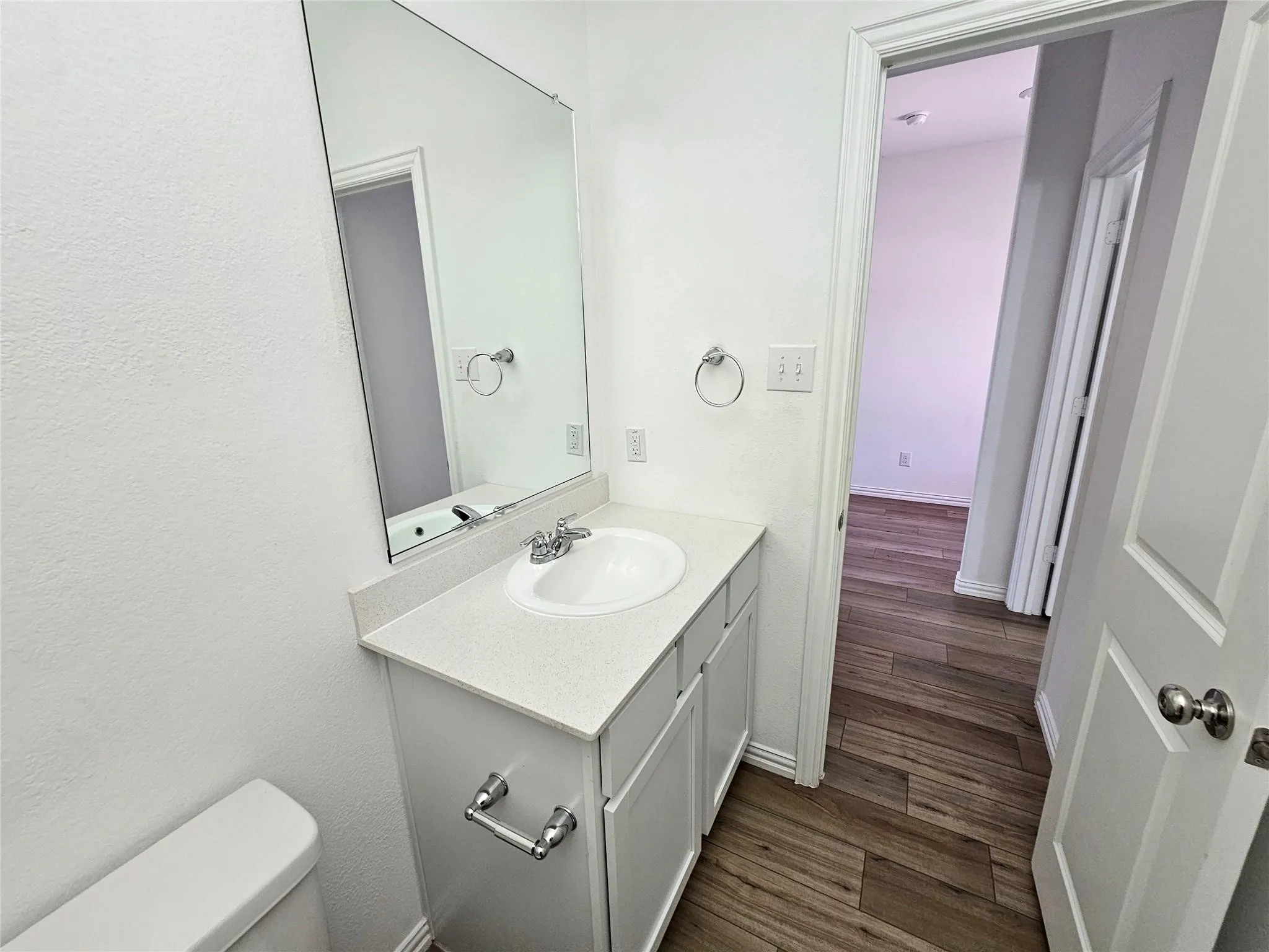Single vanity with an integrated sink, white countertop, and chrome fixtures