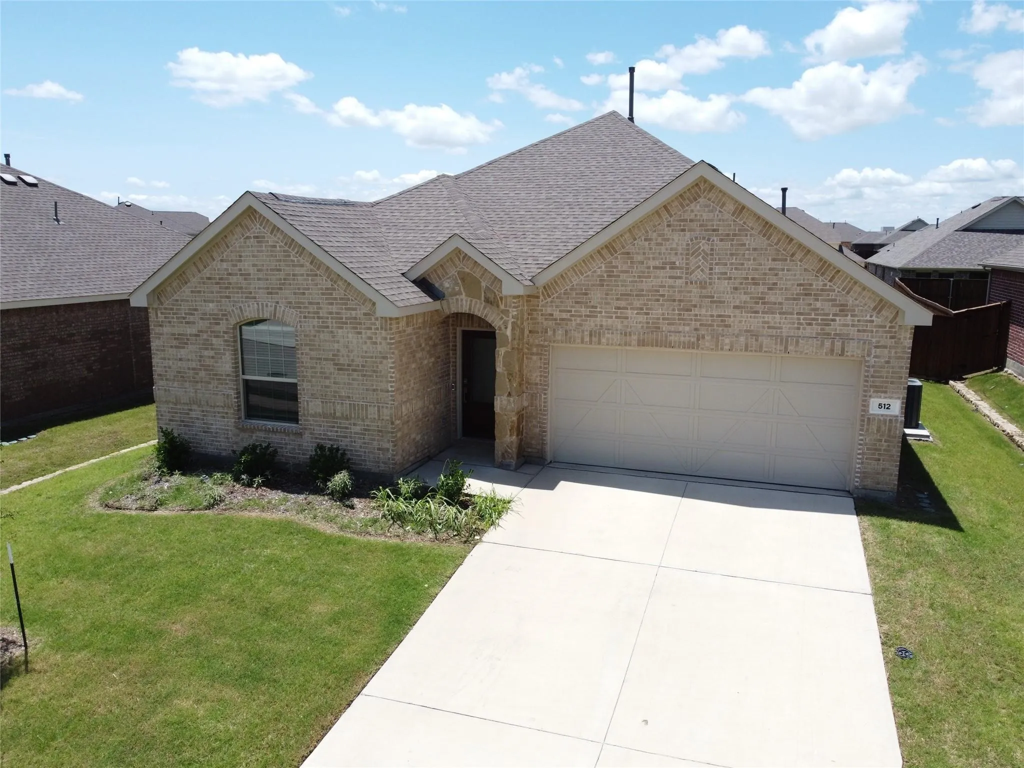 Brick exterior with an arched entry, attached garage, and a concrete driveway