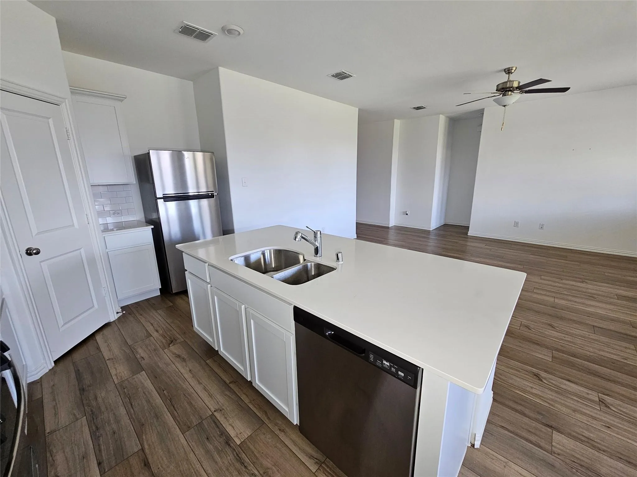 Kitchen island with dual stainless steel sink, white cabinetry, and a light-toned countertop