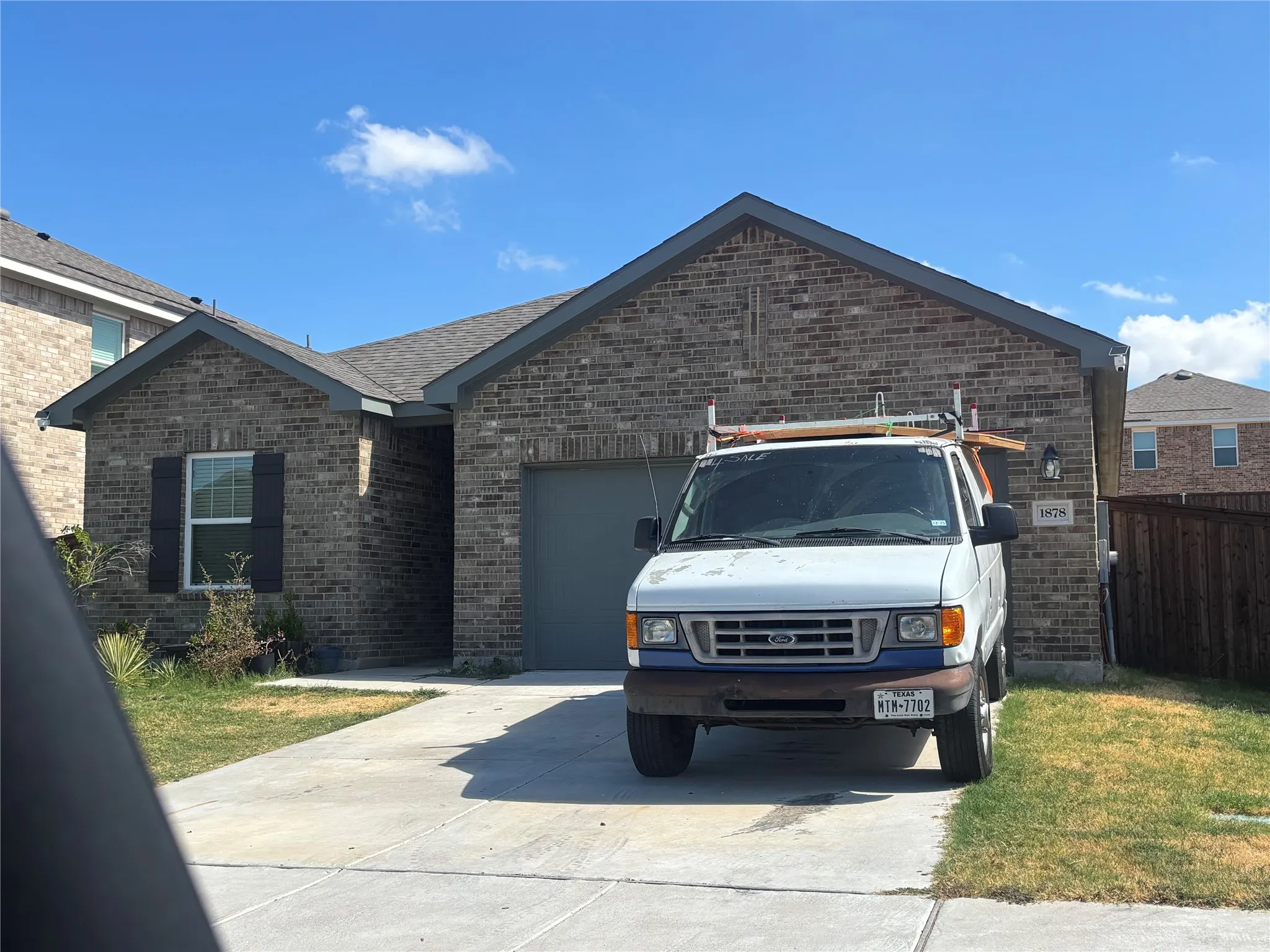 Brick exterior with gray trim, attached garage with a gray door, and a concrete driveway