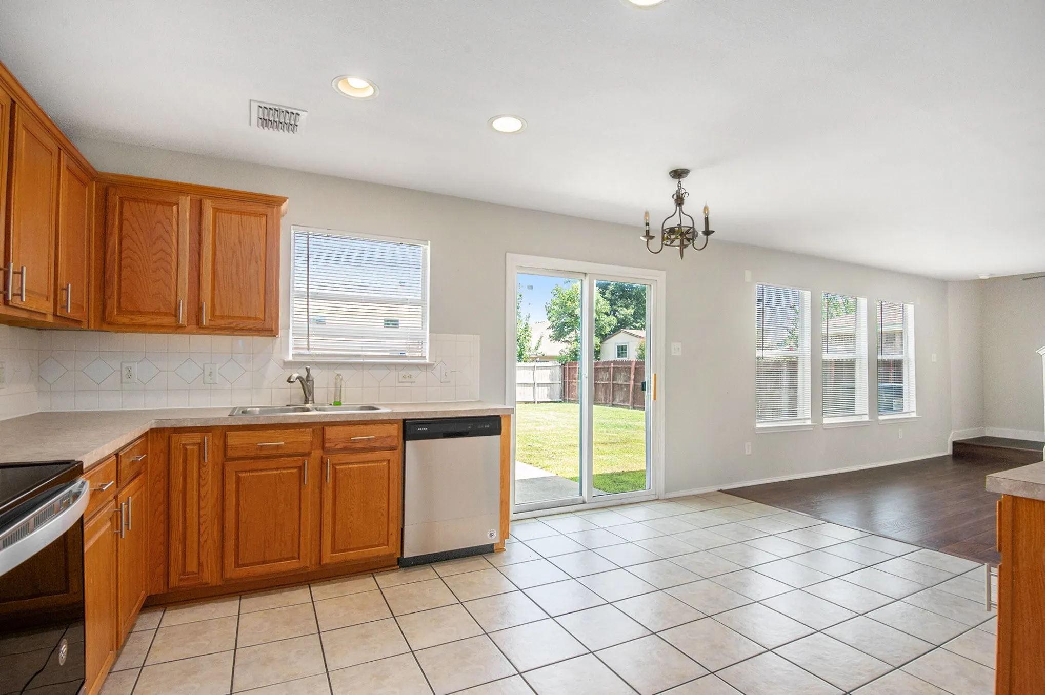 Kitchen with dishwasher, a chandelier, tasteful backsplash, light countertops, and recessed lighting