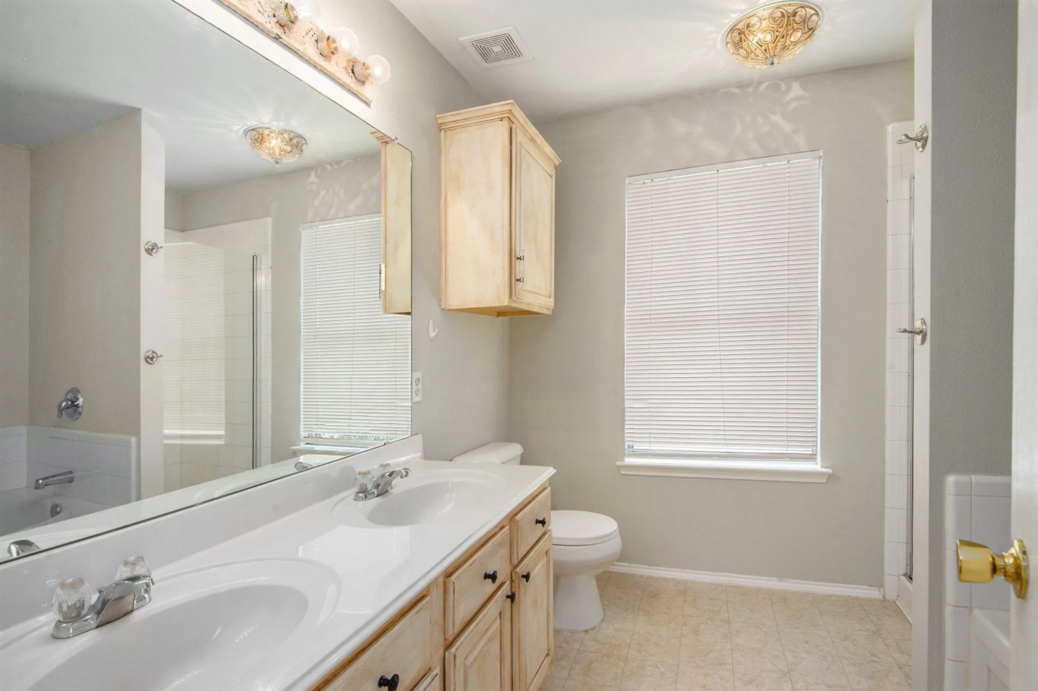 Bathroom featuring tiled shower and double vanity