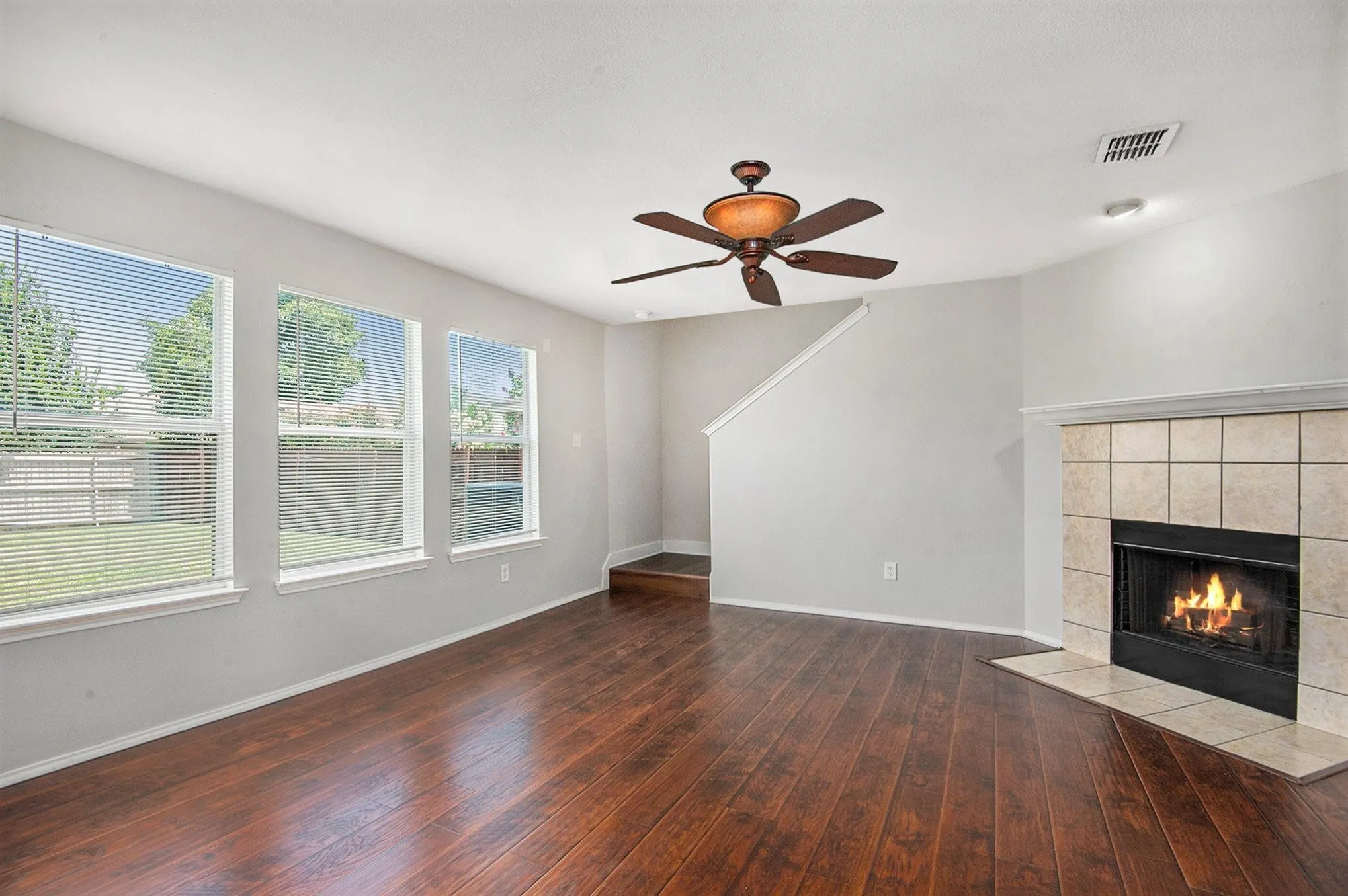 Unfurnished living room featuring a tile fireplace, hardwood / wood-style floors, and ceiling fan