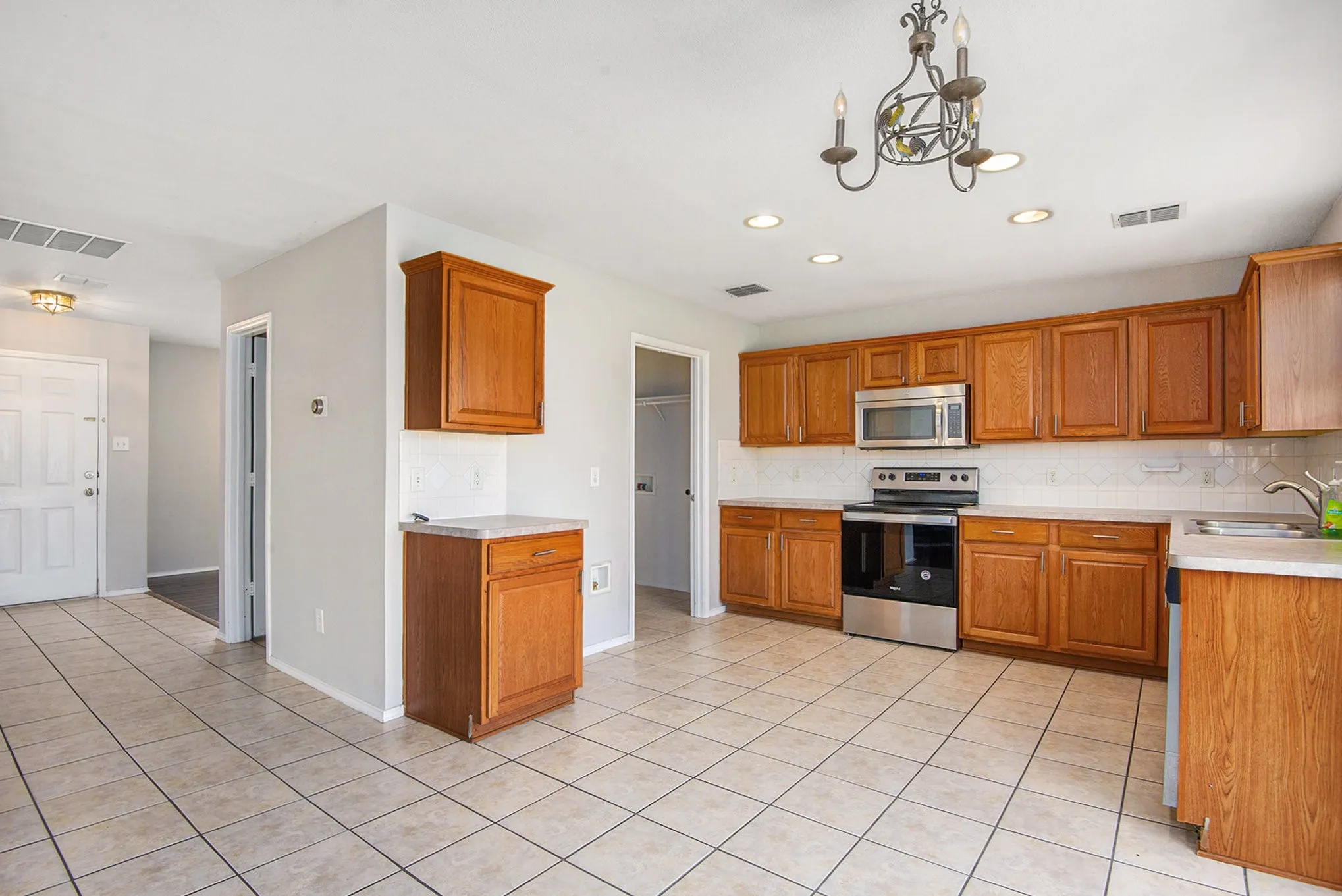 Kitchen featuring stainless steel appliances, tasteful backsplash, brown cabinets, light tile patterned flooring, and recessed lighting