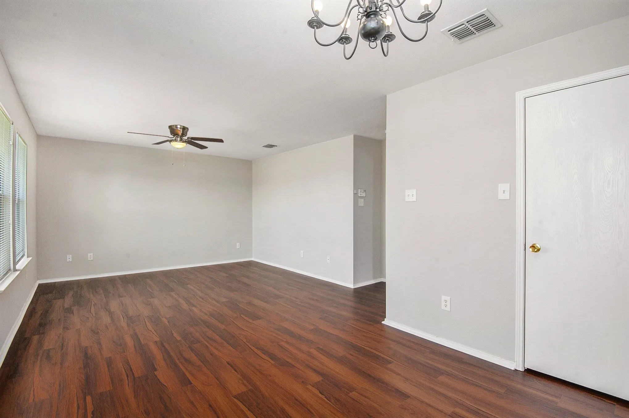 Unfurnished room with a chandelier, ceiling fan, and dark wood-style floors