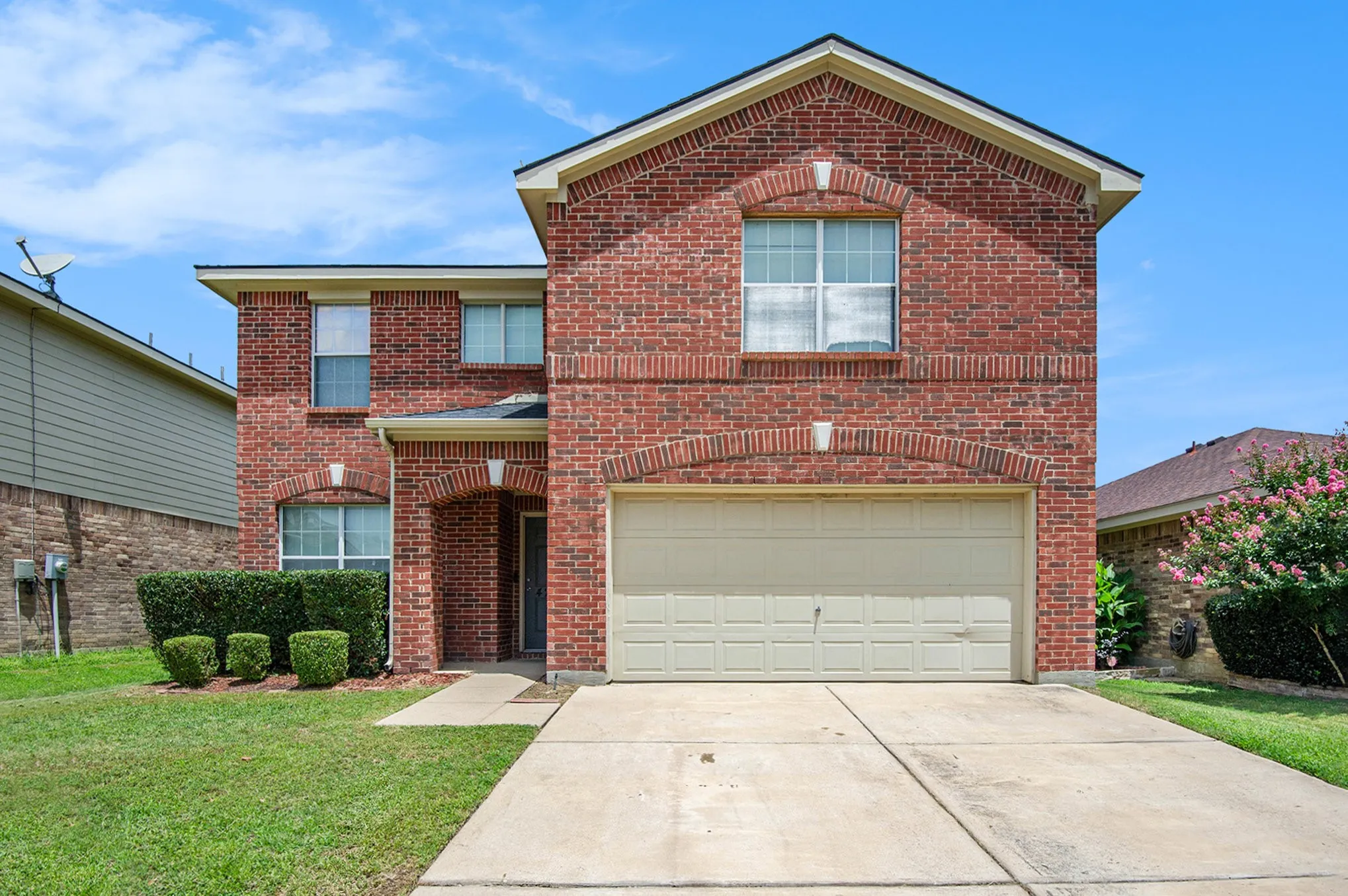 Traditional-style home featuring concrete driveway, brick siding, a garage, and a front yard
