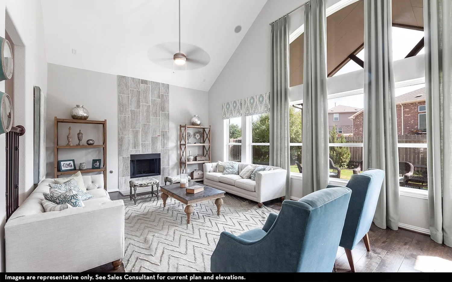 Vaulted ceilings with a ceiling fan and light fixture, a fireplace with a stone-tiled surround, and large windows with transoms