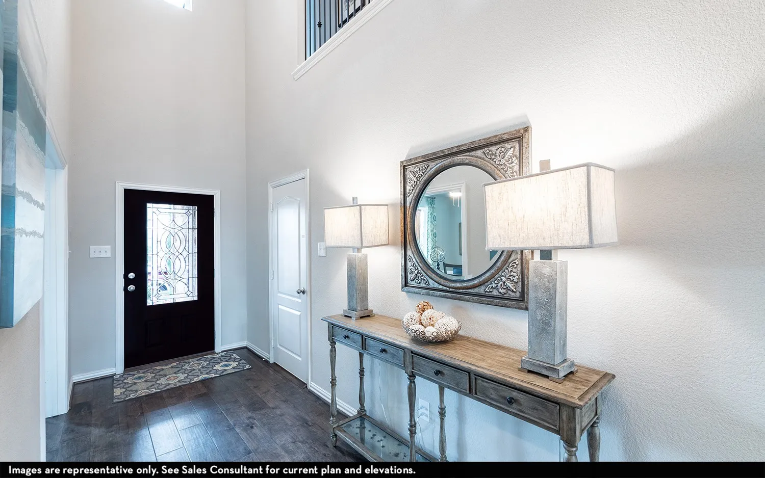 Two-story foyer with dark wood-finish flooring, a decorative glass front door, and a built-in console table