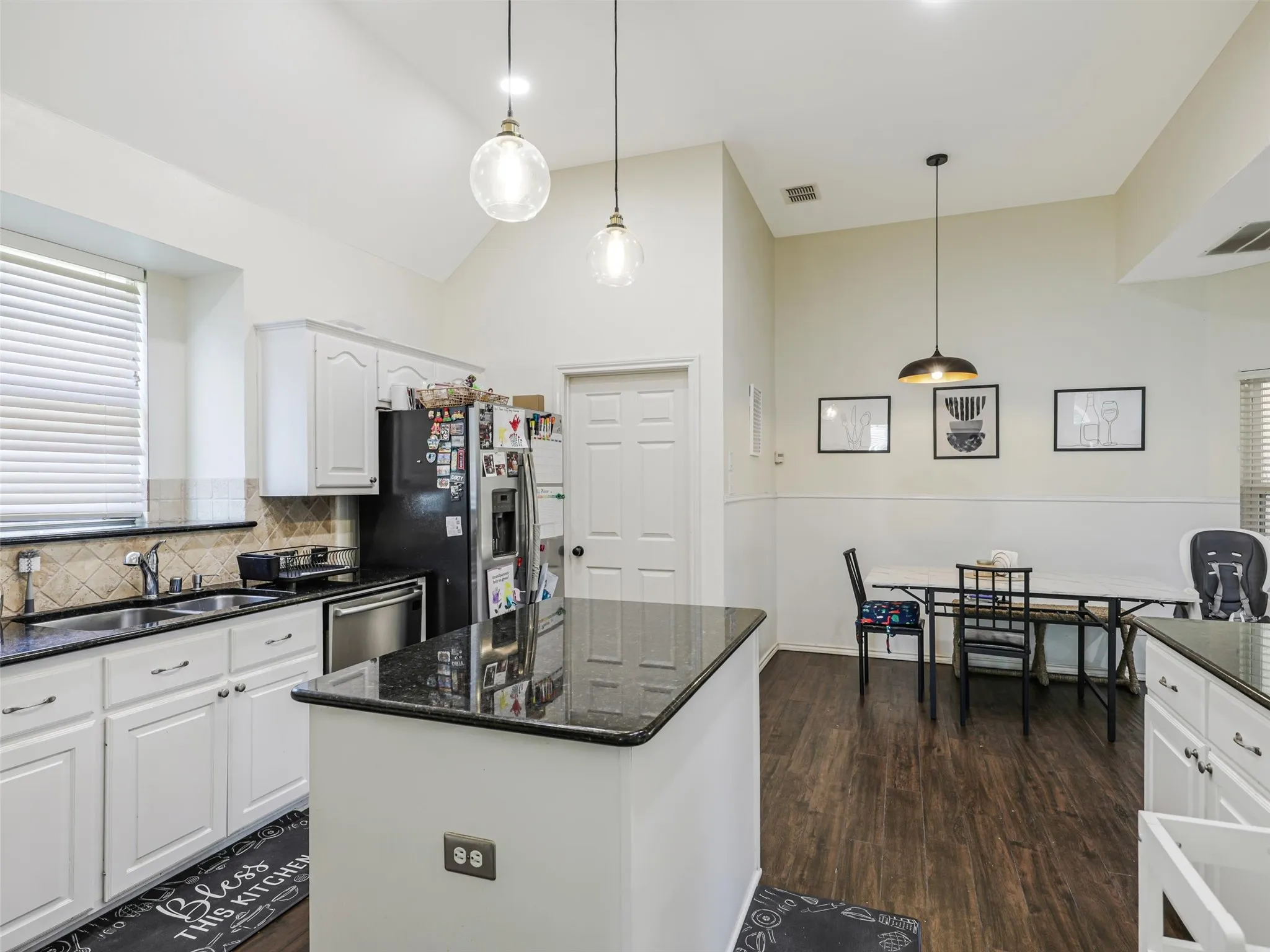 Kitchen featuring white cabinetry, dark countertops, wood-finish flooring, a center island, and a tile backsplash