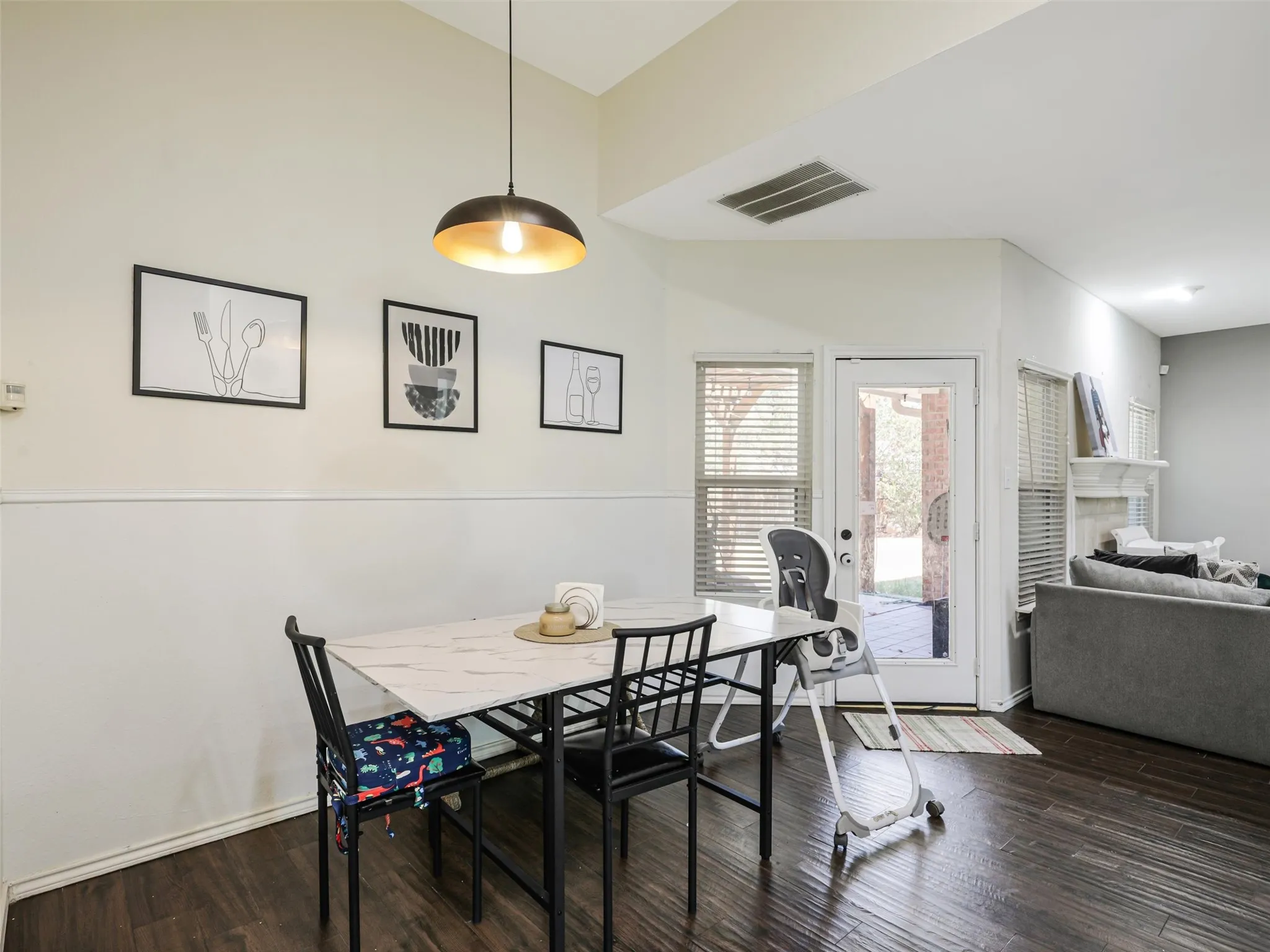 Dining area with wood-finish flooring, a contemporary pendant light fixture, and a glass-paneled door