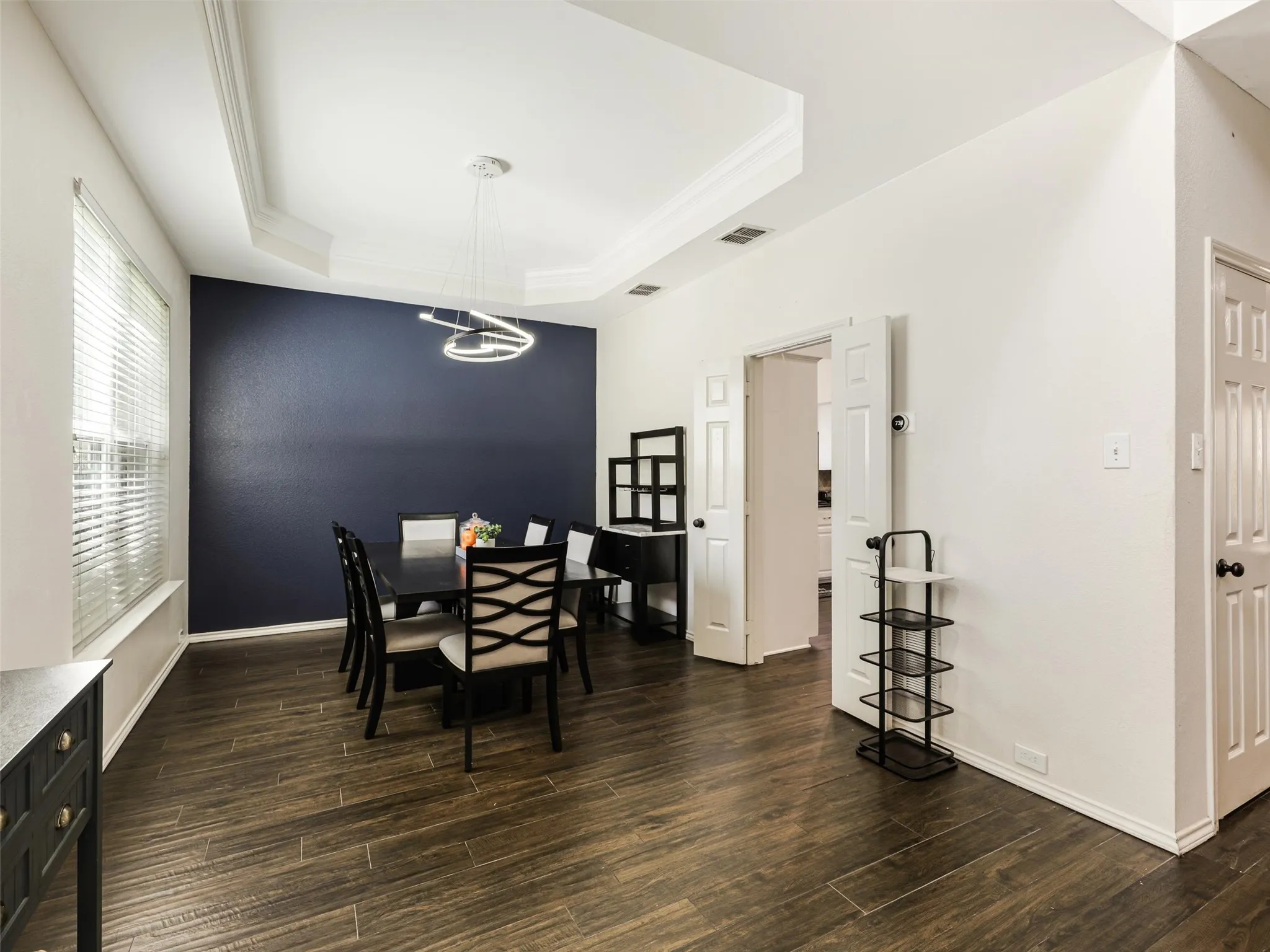 Tray ceiling with crown molding, contemporary chandelier, wood-finish flooring, and white interior doors
