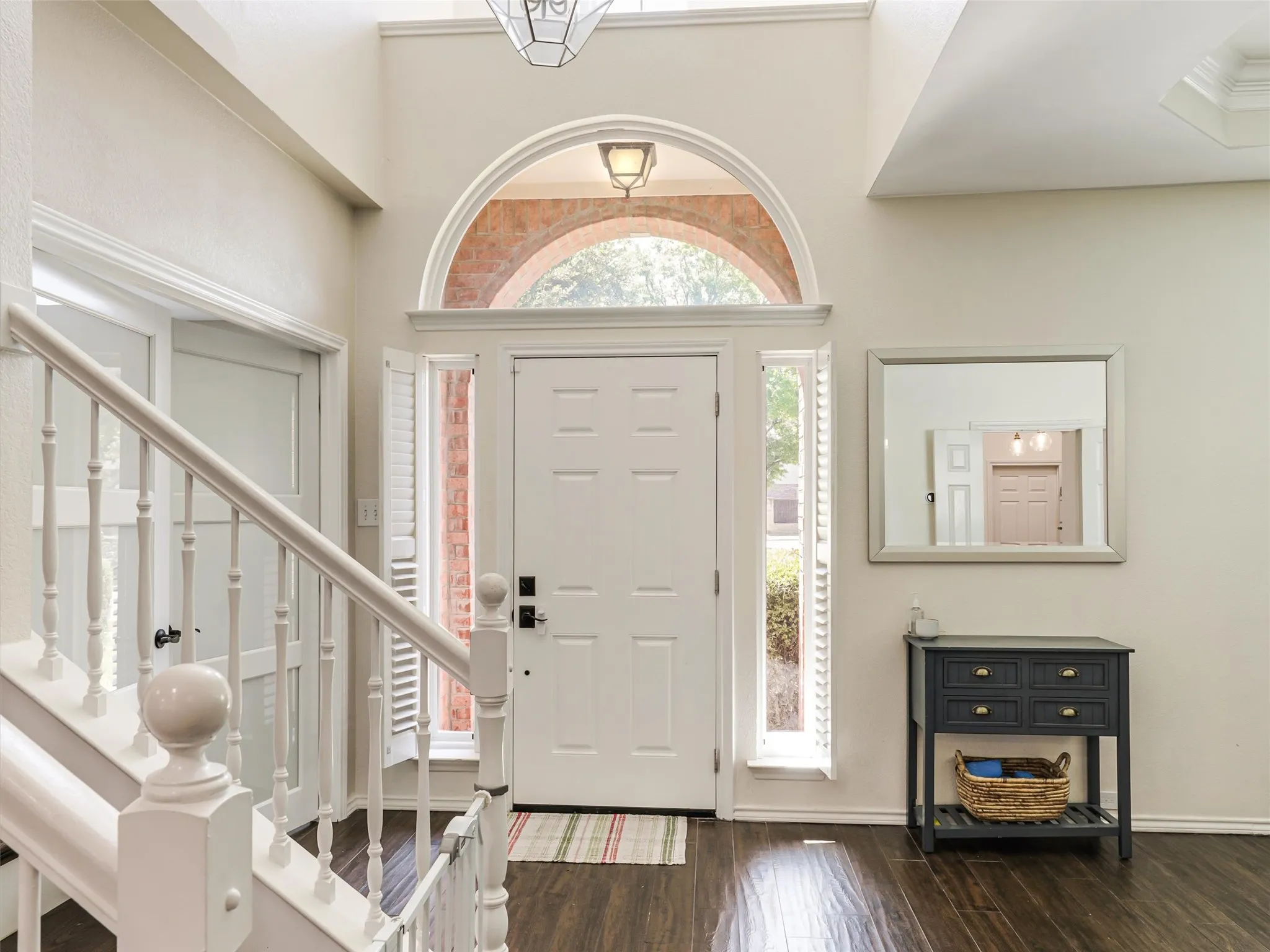 Two-story foyer with high ceilings, dark wood-finish flooring, and white painted balusters