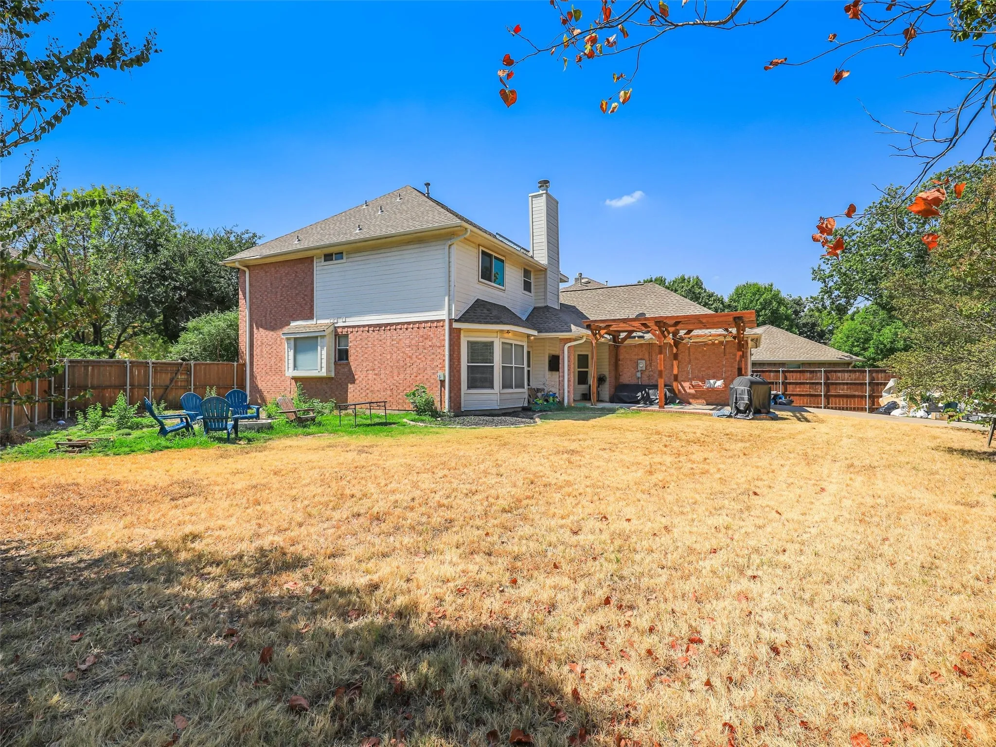 Expansive backyard featuring a wood pergola over a paved patio, a bay window, and a privacy fence