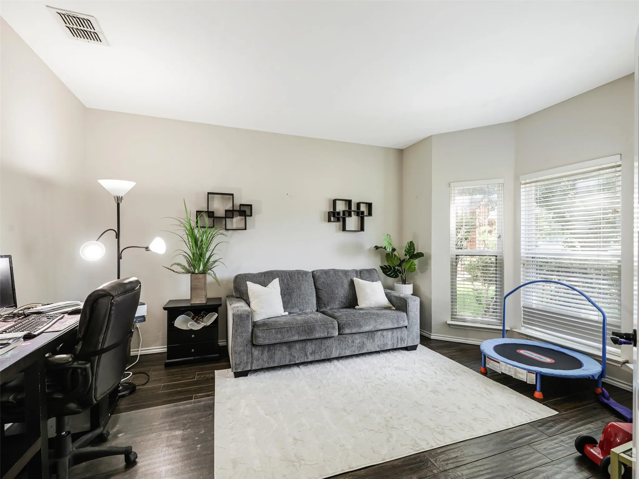 Room featuring wood-finish flooring, two window openings, and neutral wall tones