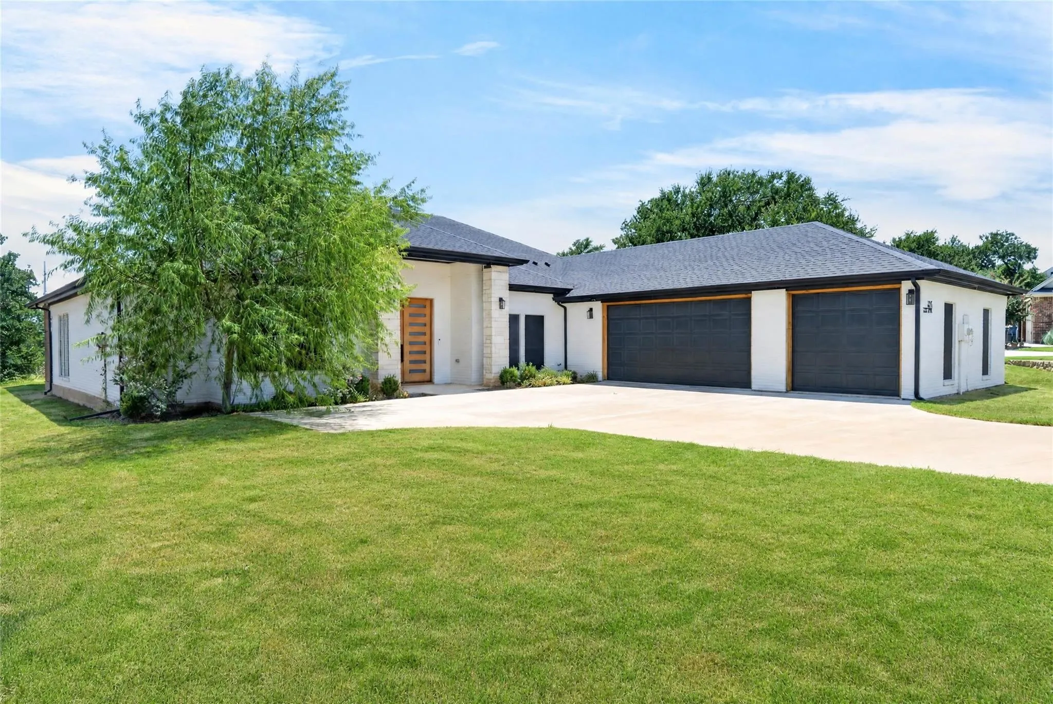 Contemporary architecture with a light-colored brick exterior and dark shingle roof