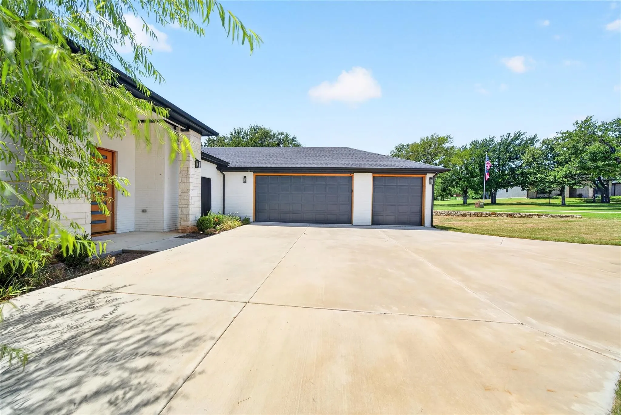 Exterior featuring a light-colored stucco and stone facade, a multi-panel wood-finish entry door, and a two-car garage with dark paneled doors