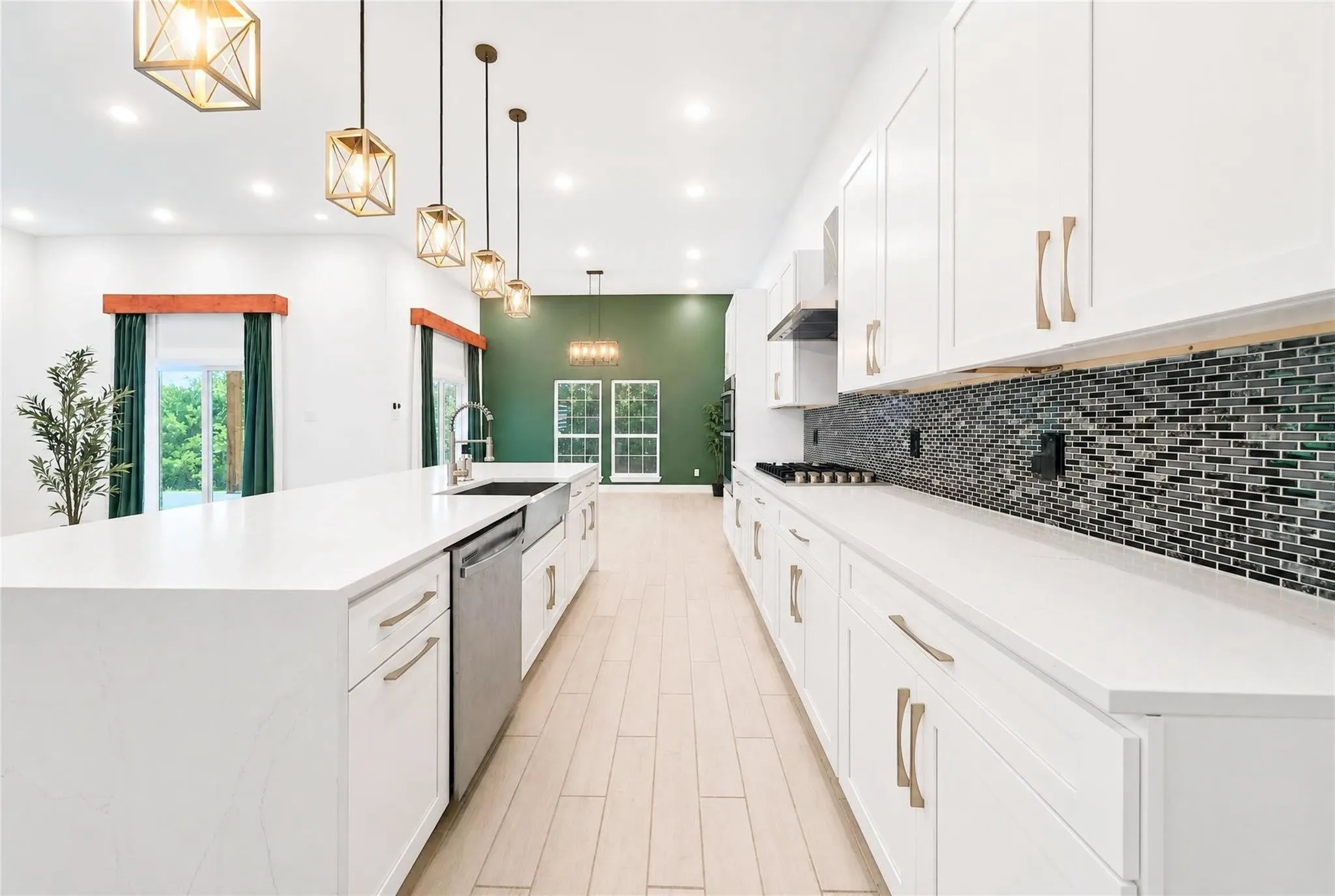 Spacious kitchen featuring an expansive central island, white cabinetry, integrated stainless steel appliances, and a unique tile backsplash