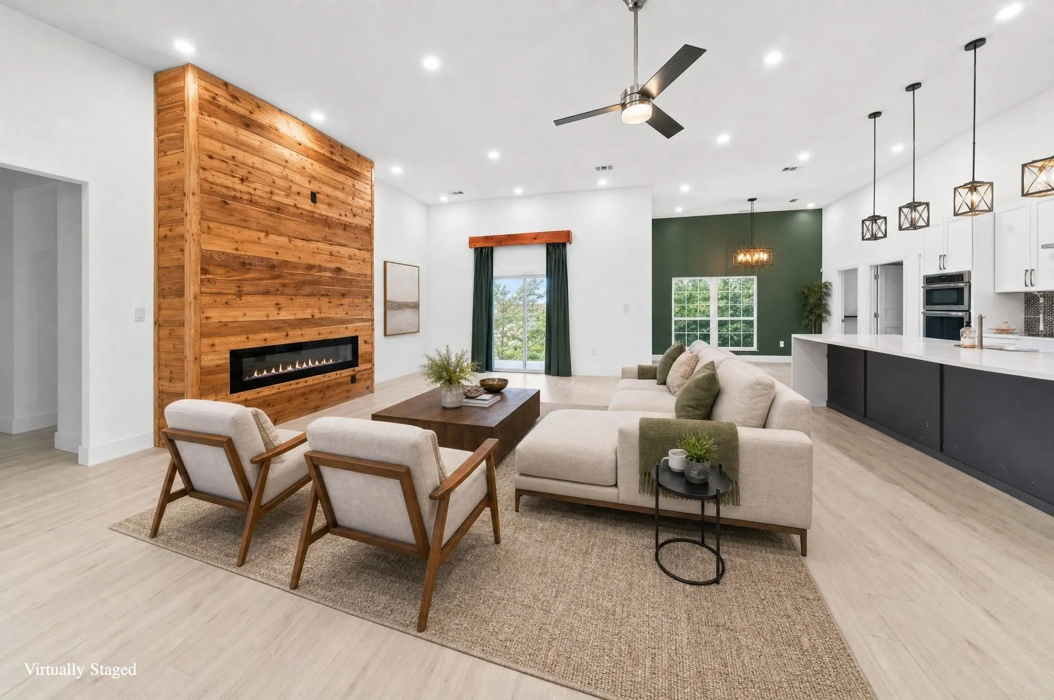 Wood-finish flooring throughout, wood plank accent wall with an integrated linear fireplace, recessed lighting, ceiling fan, and built-in kitchen cabinetry with pendant lighting