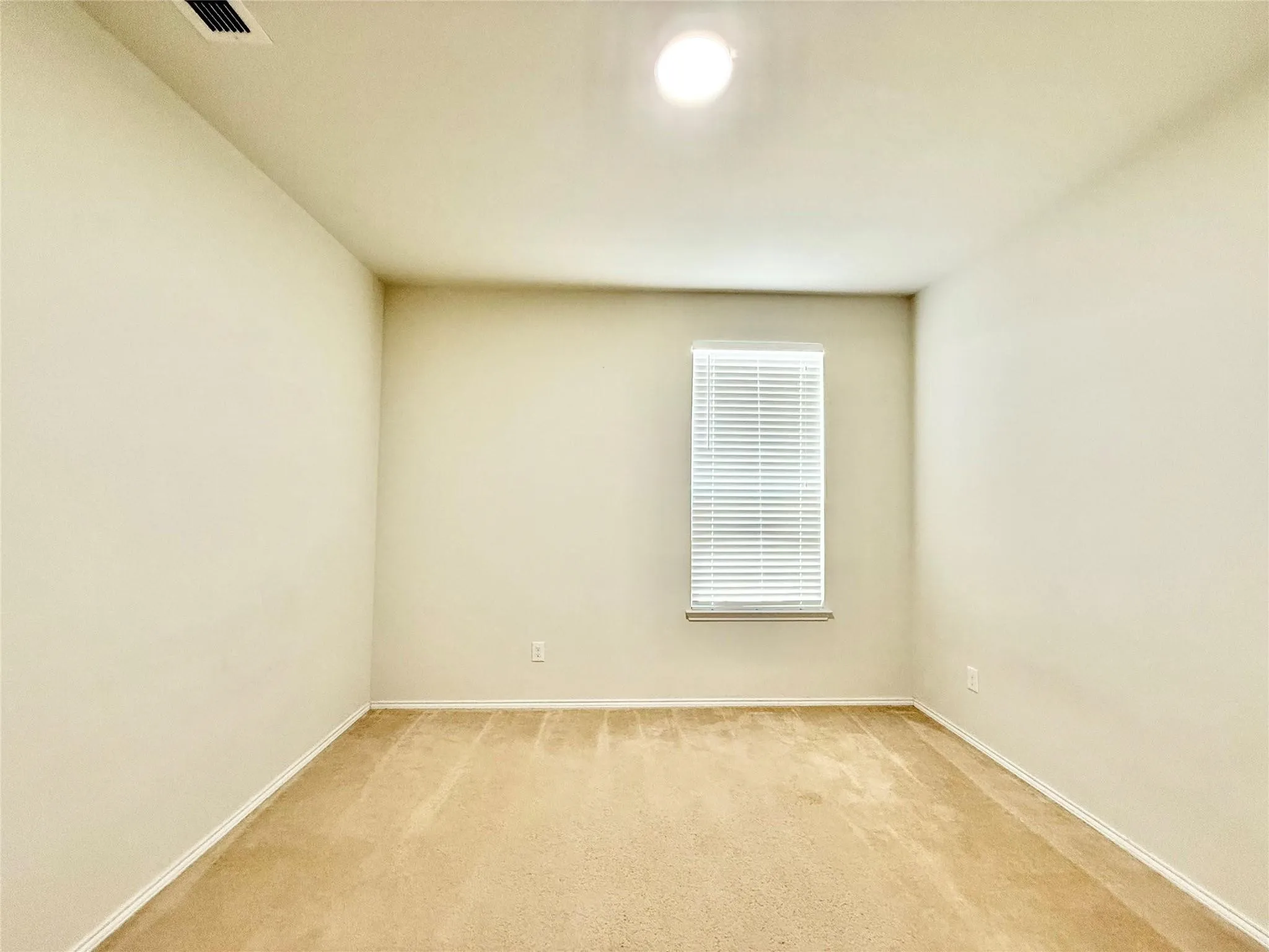 Neutral wall paint, plush carpet flooring, single window with blinds, recessed ceiling light