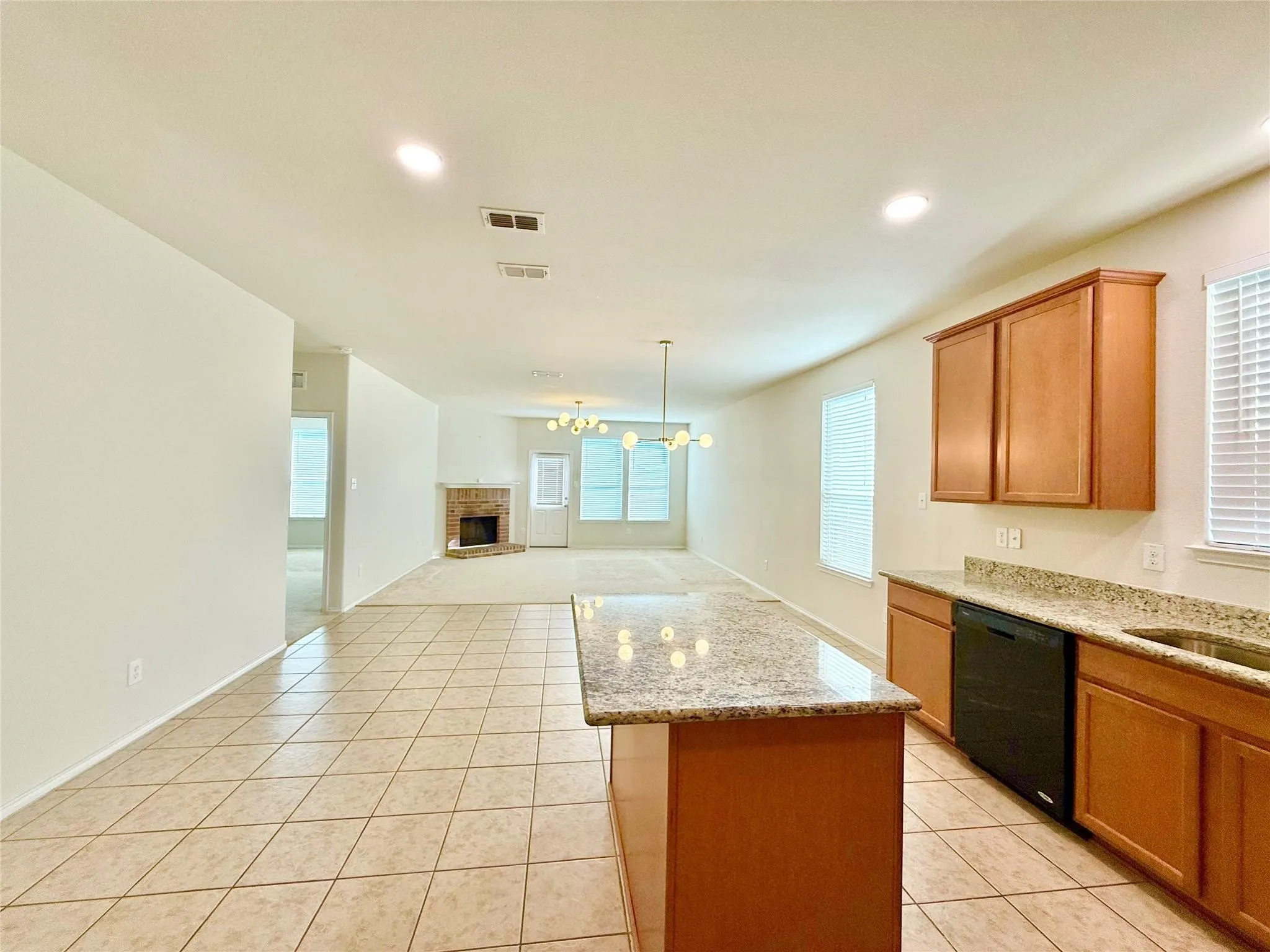 Kitchen with granite countertops, wood cabinetry, built-in dishwasher, and tile flooring