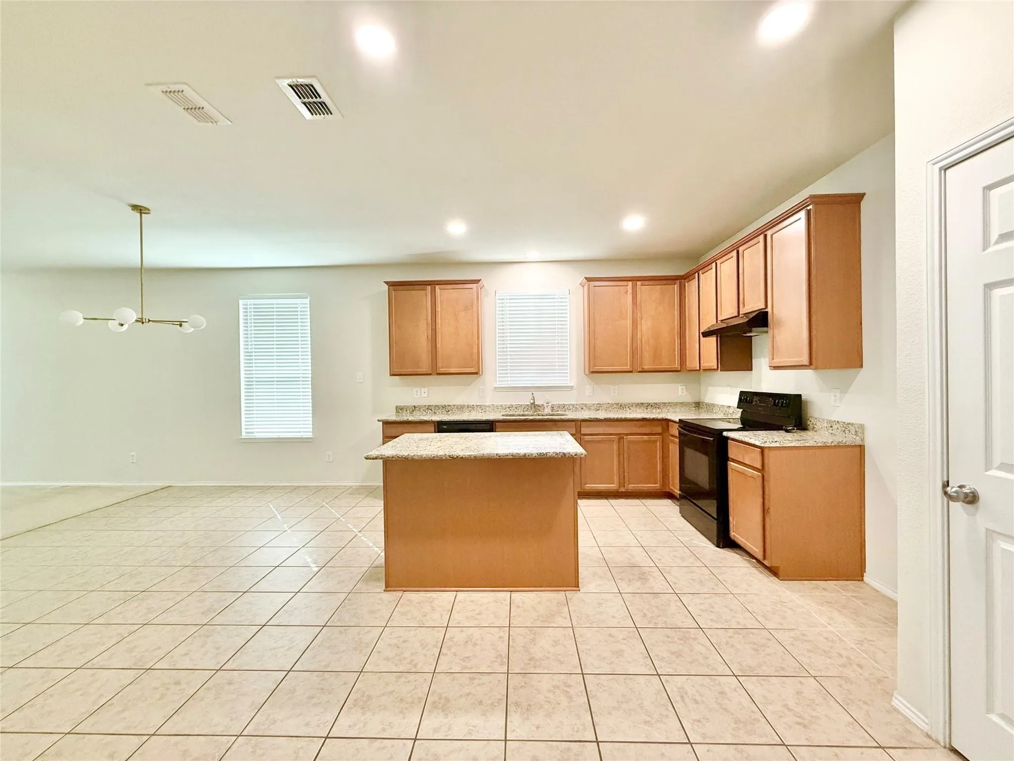 Kitchen featuring wood-finish cabinetry, light-toned countertops, and a central island