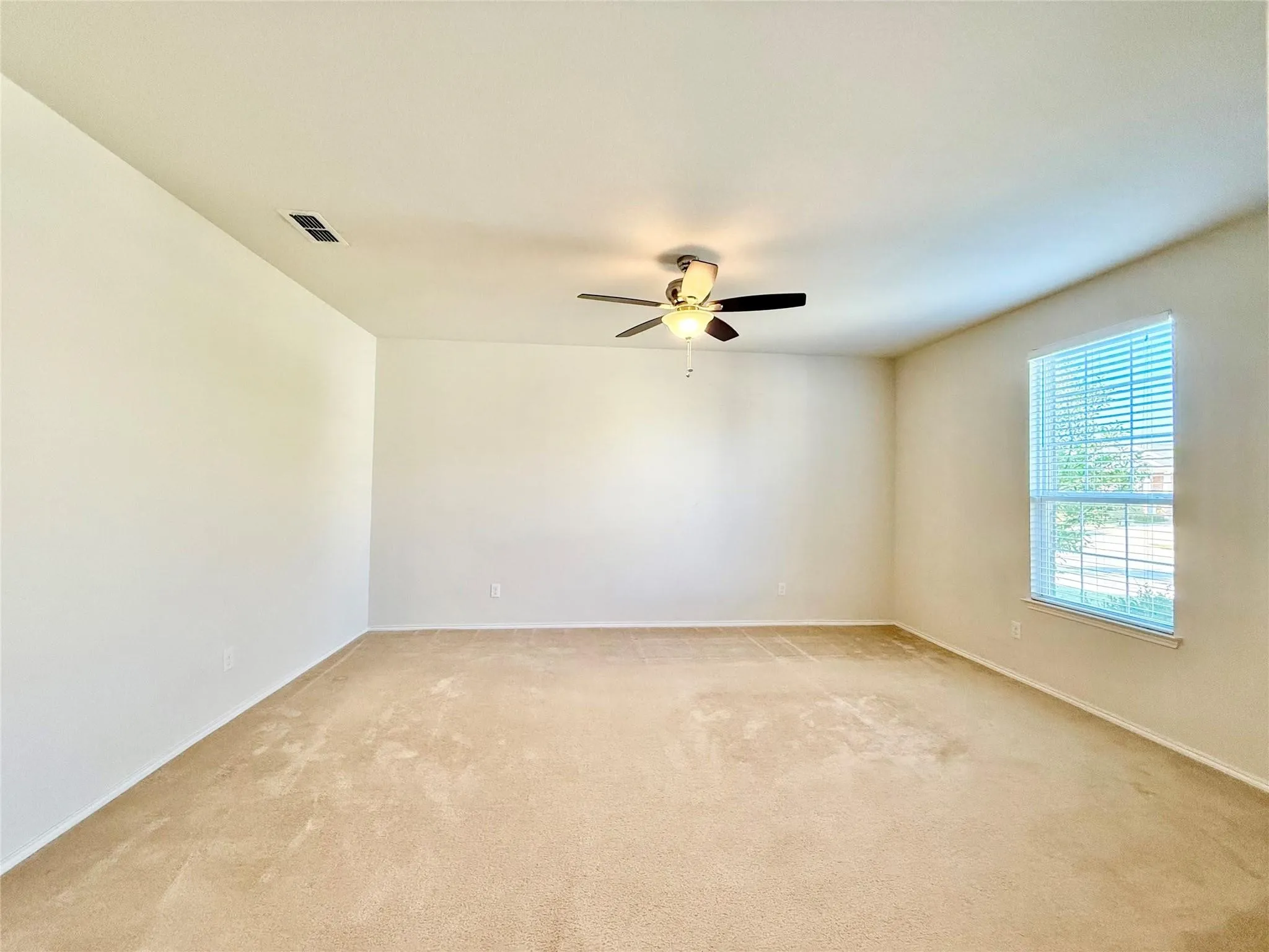 Spacious room featuring carpeting, neutral wall color, and a ceiling fan