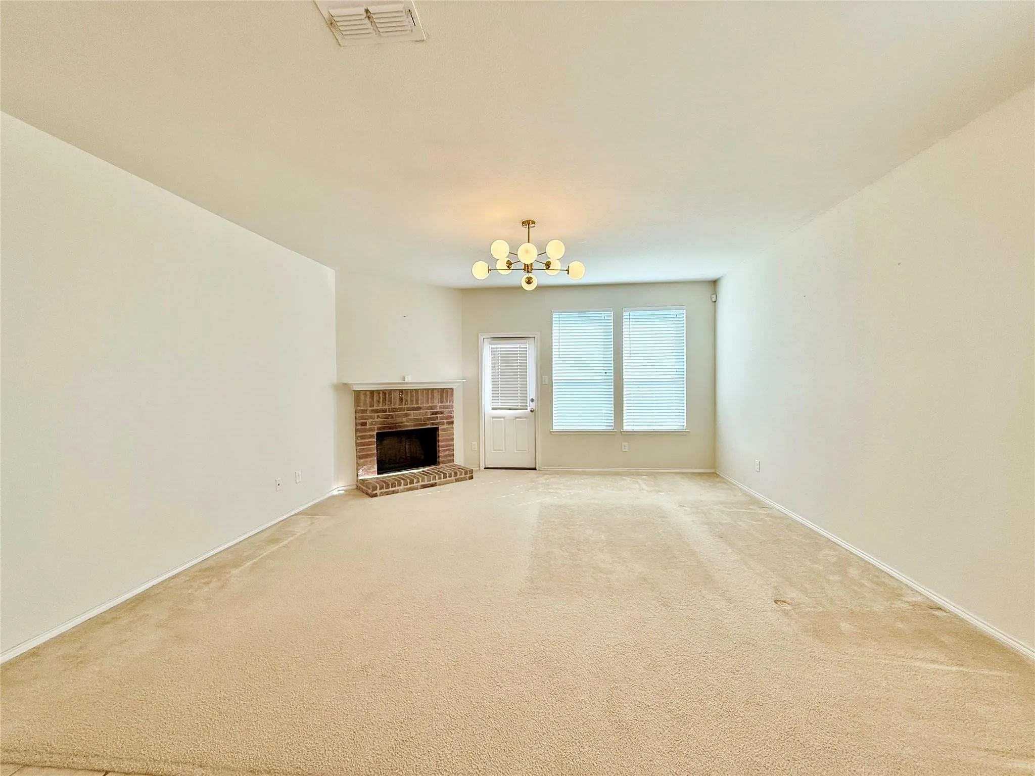 Brick-surround fireplace with hearth, two windows with blinds, and ceiling-mounted light fixture