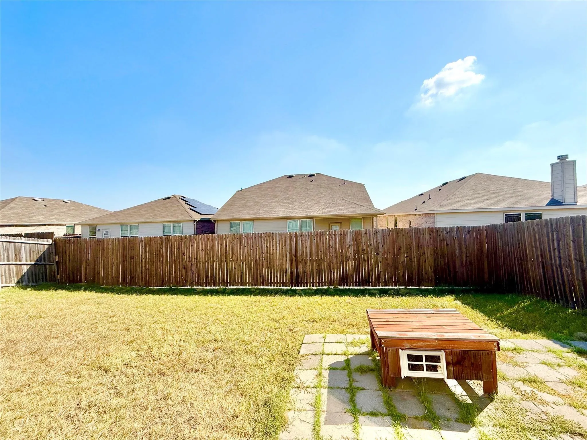 Expansive backyard featuring a wood fence, concrete paver patio area, and a grassy lawn