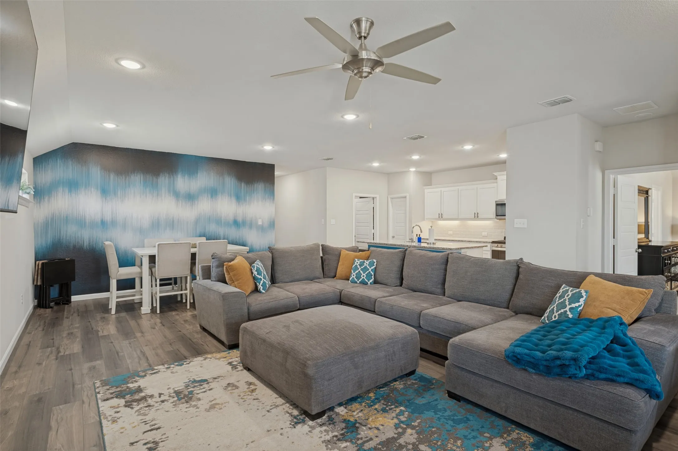 Open-concept living area with wood-finish flooring, recessed lighting, and a ceiling fan