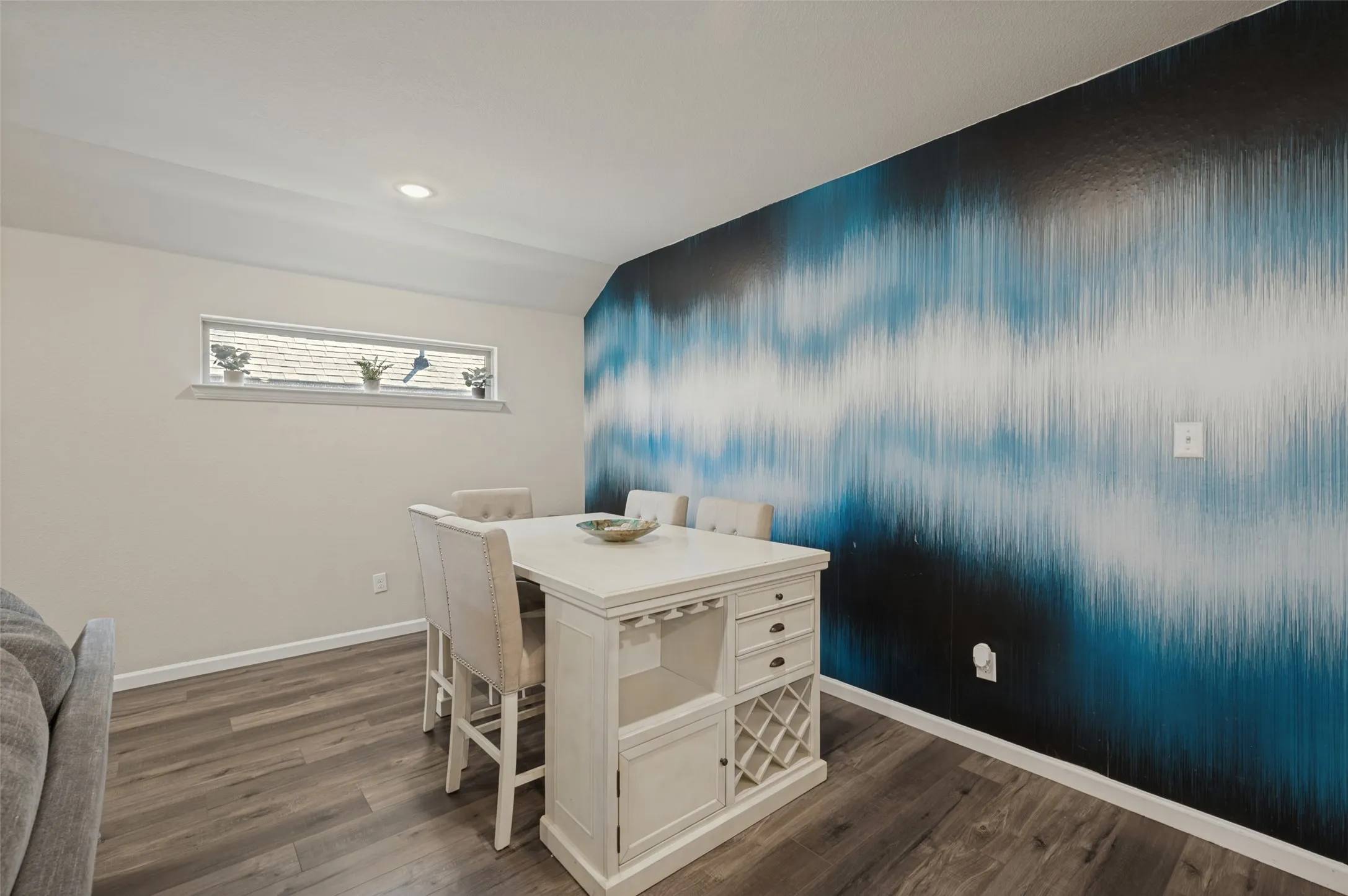 Recessed ceiling lighting, wood-finish flooring, accent wall with graphic pattern, horizontal window, and white trim molding