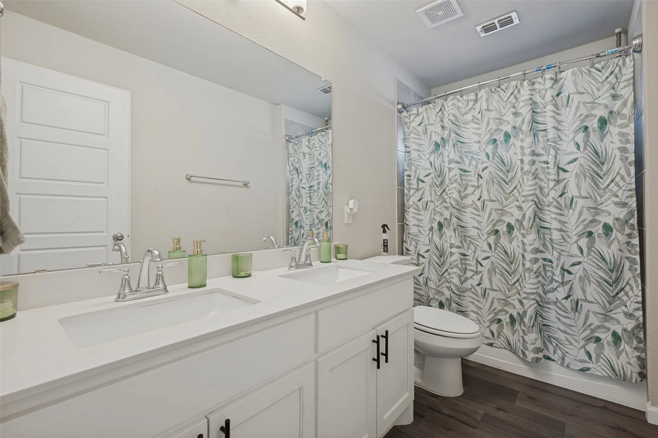 Dual vanity with integrated sinks, chrome fixtures, white cabinetry with black hardware, and a shower-tub combination