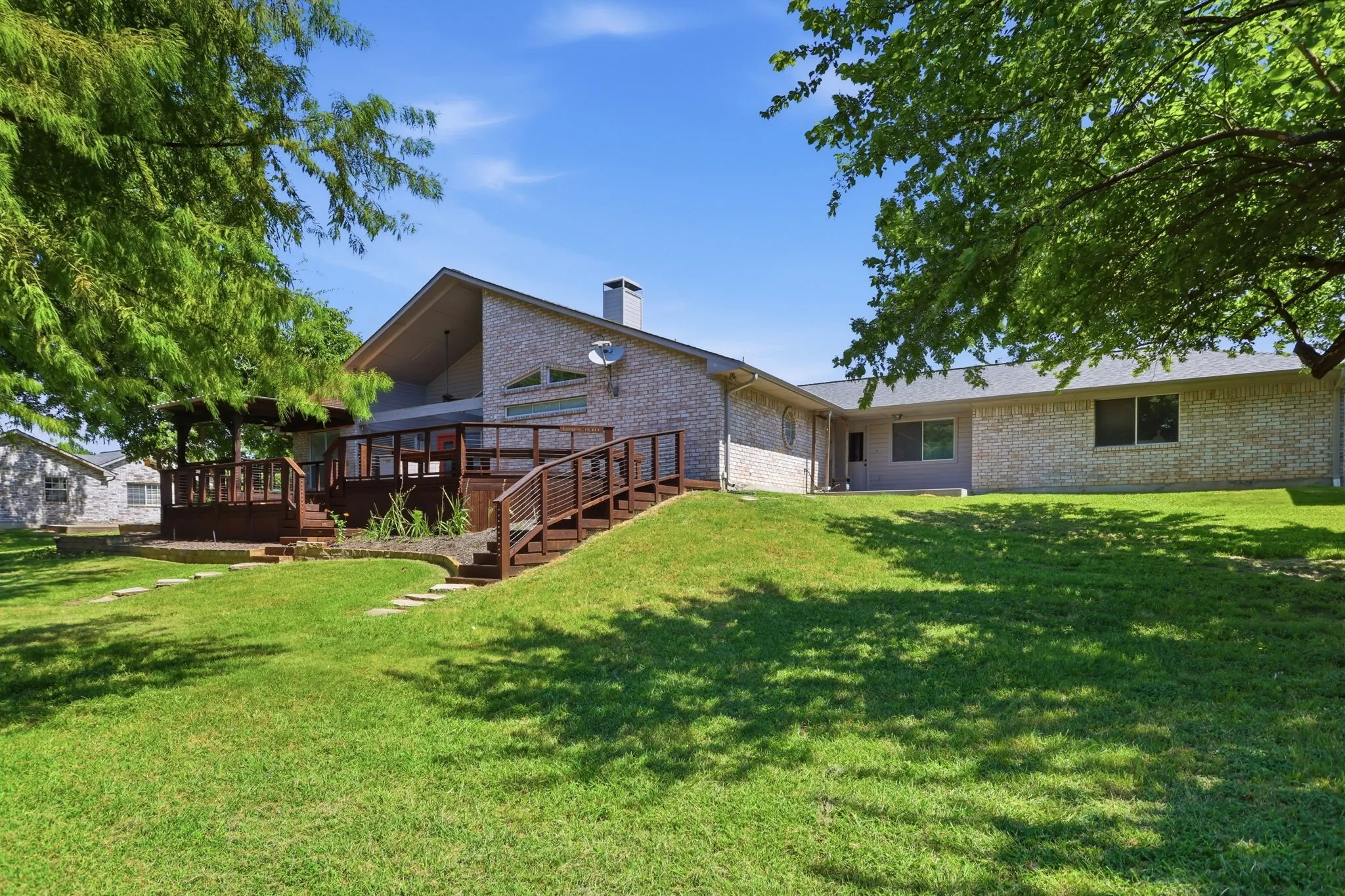 Expansive green space with a multi-level wood deck and integrated pergola