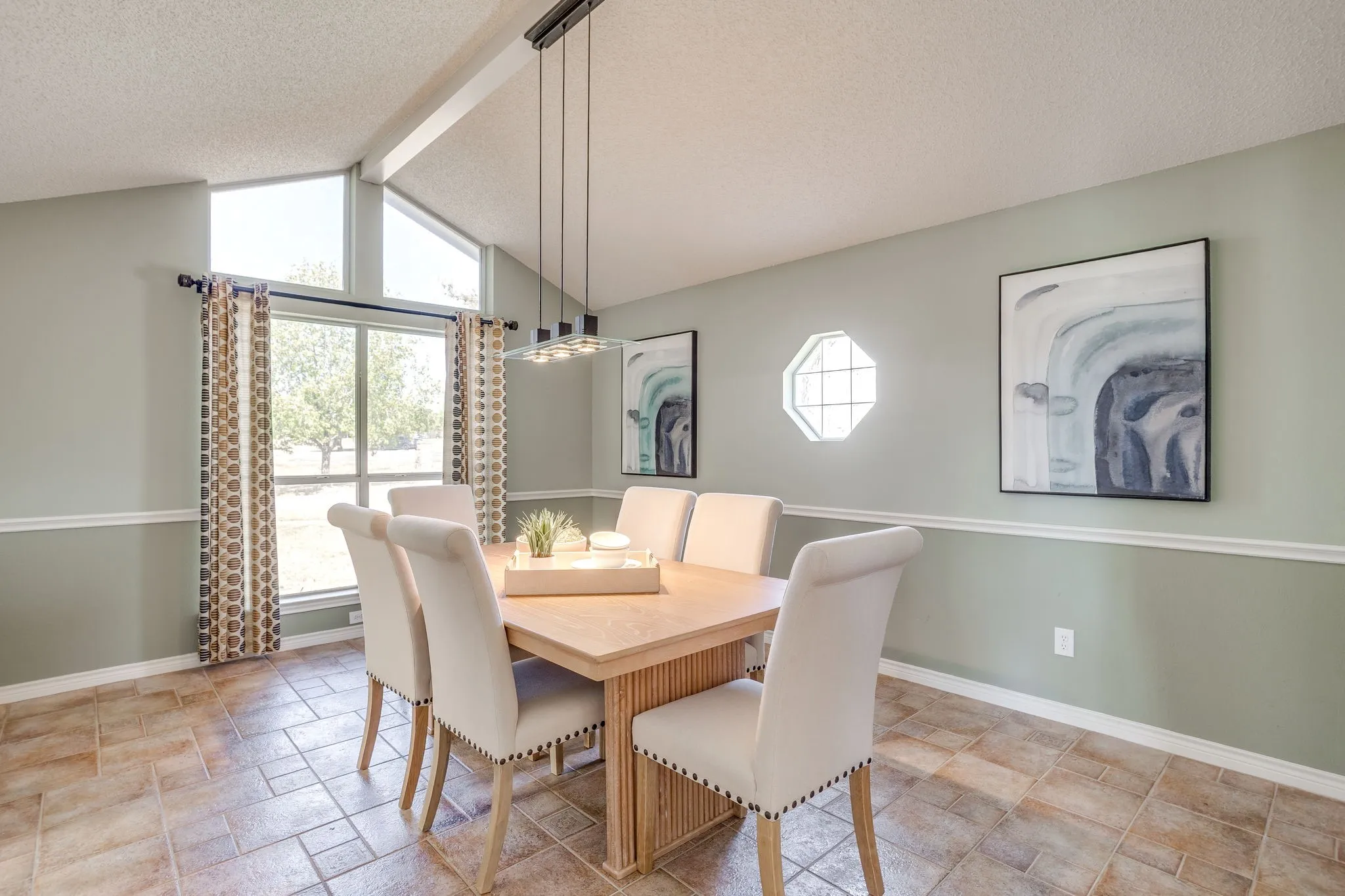 Vaulted ceiling with exposed beam, transom windows, octagon window, chair rail molding, and tile flooring