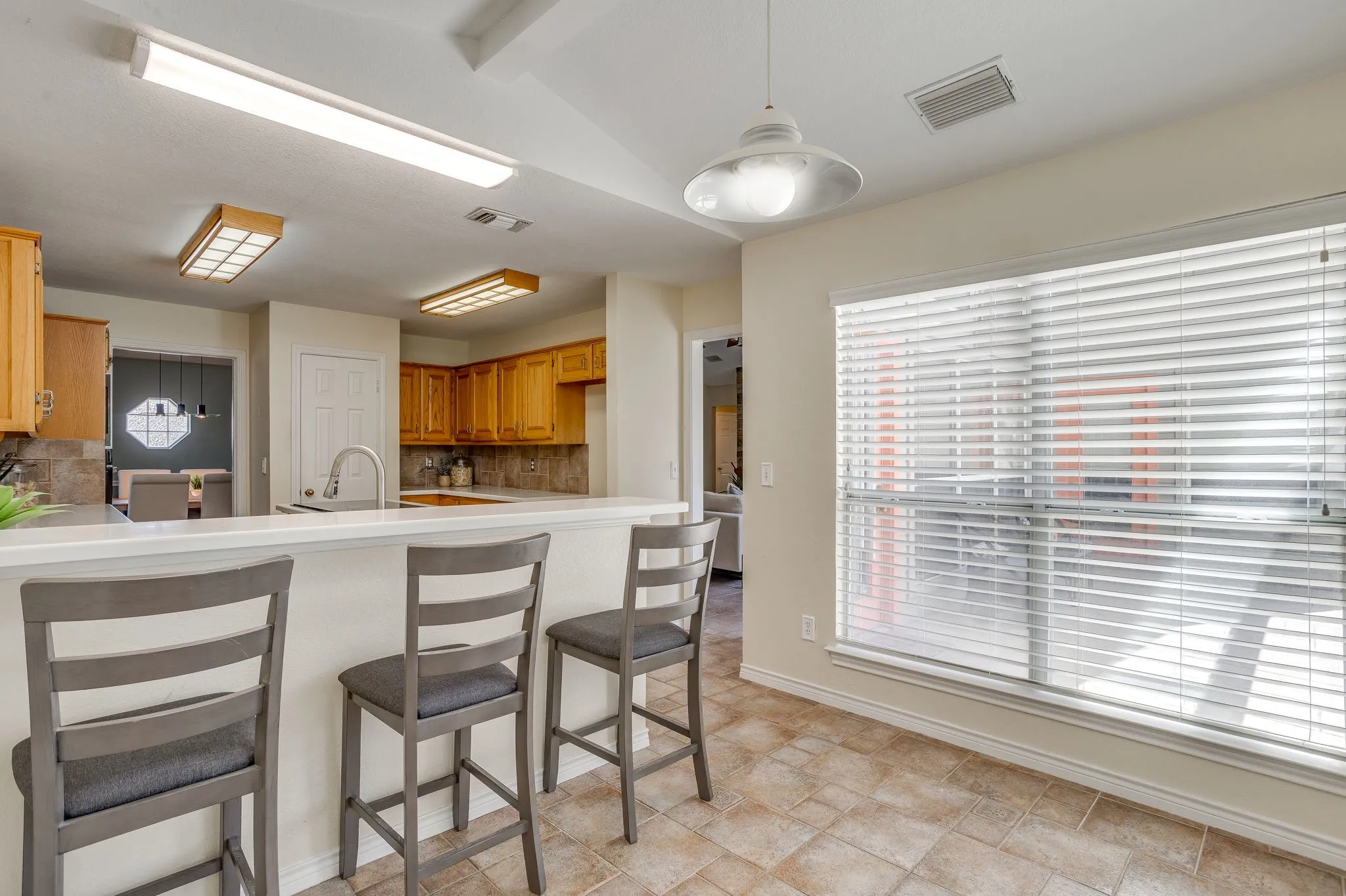 Kitchen featuring light wood cabinetry, a breakfast bar, a stainless steel gooseneck faucet, and a tile backsplash