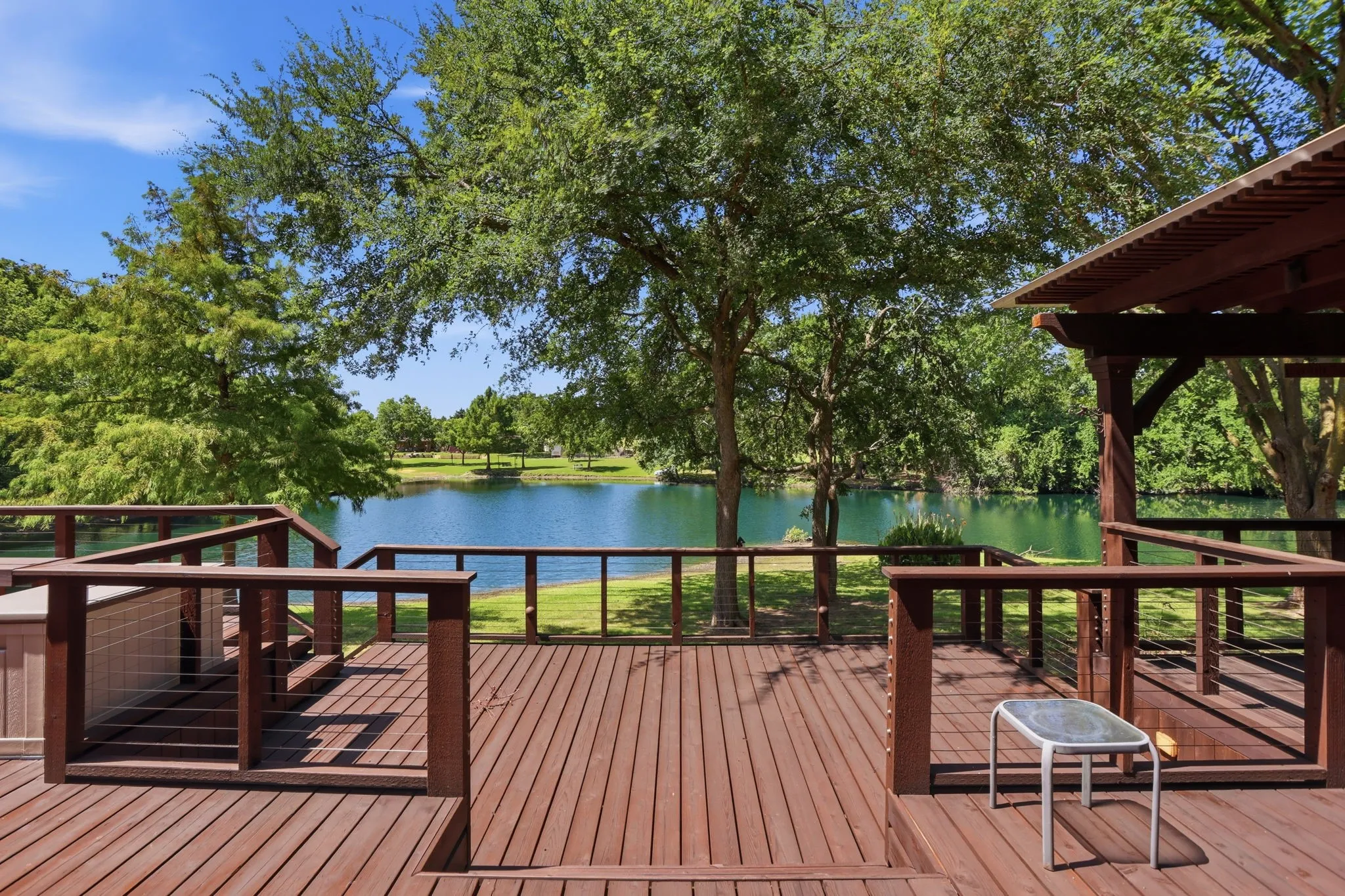 Expansive wood deck with cable railings overlooking a serene body of water