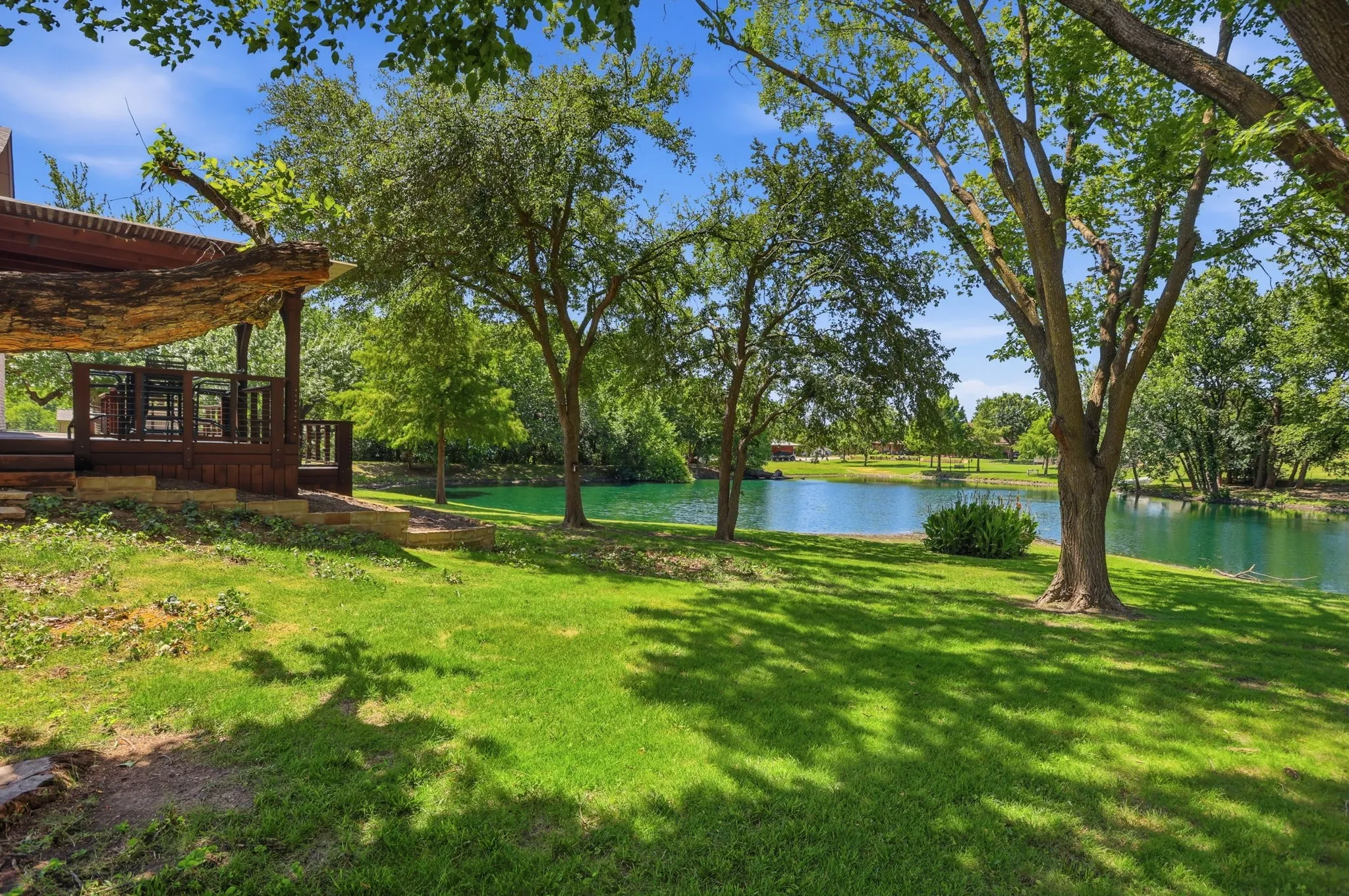 Expansive backyard with a manicured lawn, mature trees, and a tranquil pond