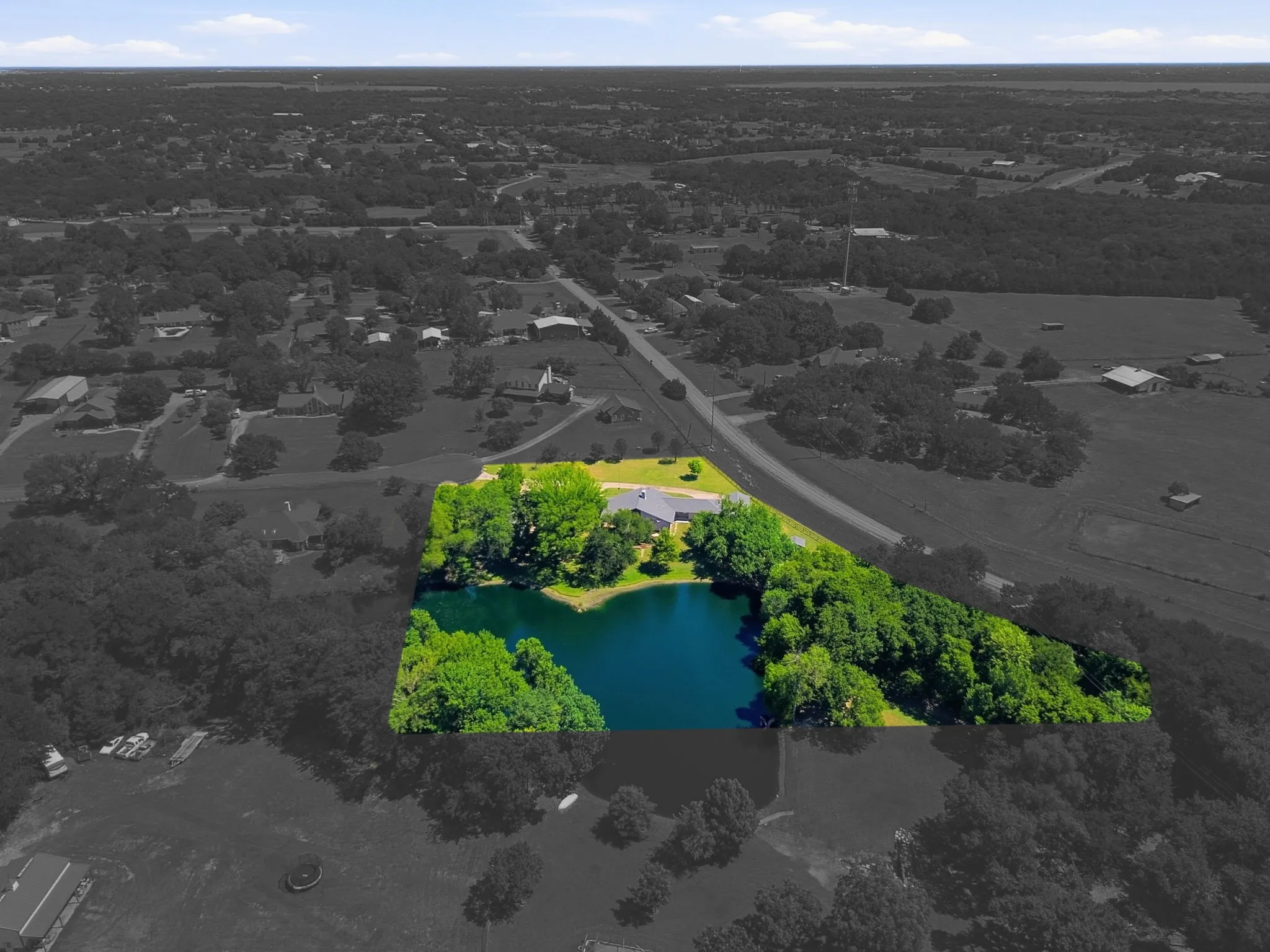 Expansive property featuring a private pond, mature trees, and a residential structure with an attached garage