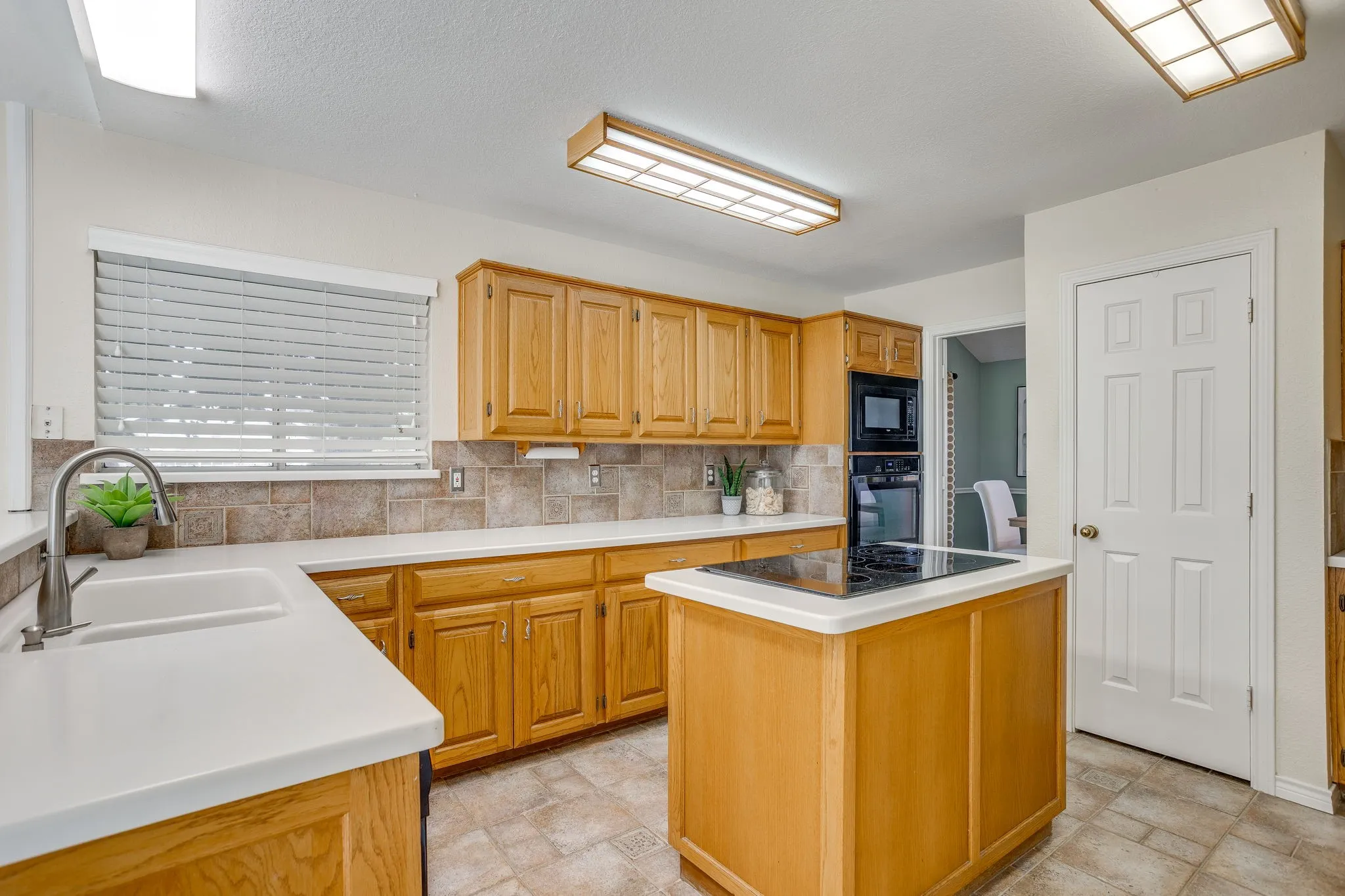 Kitchen with wood cabinetry, light countertops, and an integrated oven and microwave