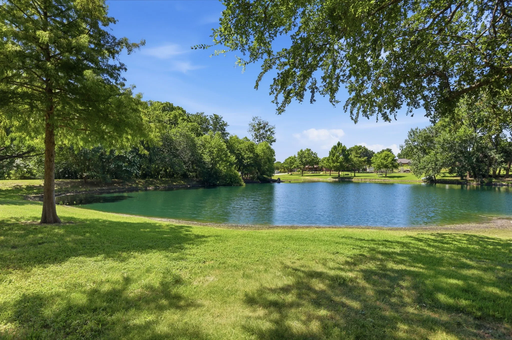 Expansive pond with surrounding mature trees and manicured lawn