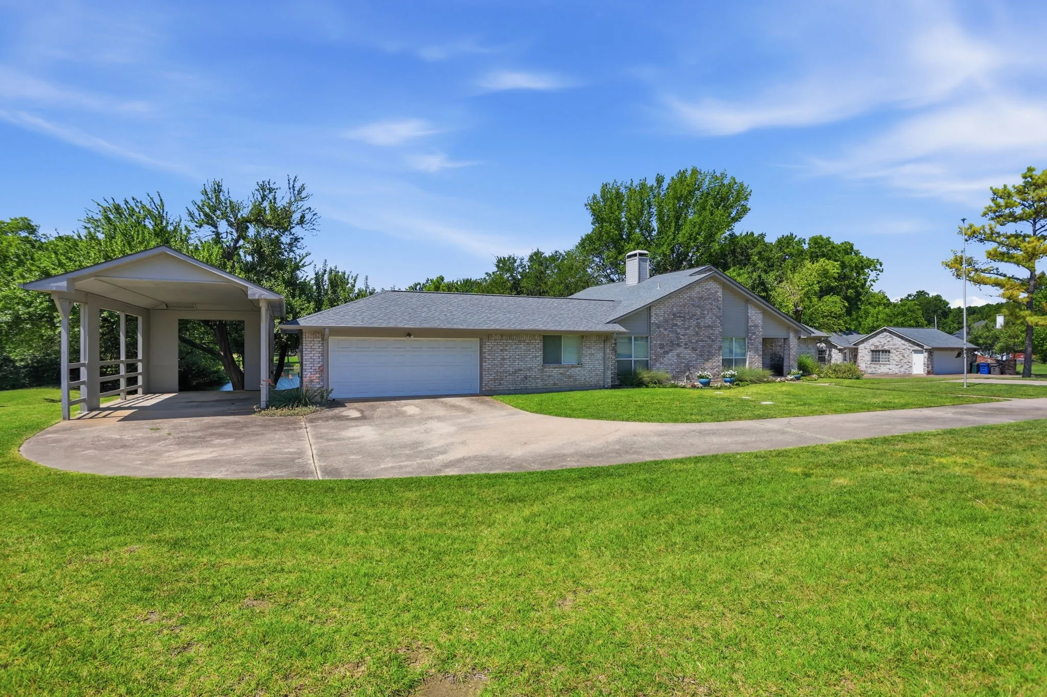 Brick exterior residence with an attached two-car garage, separate RV carport, and a detached tandum 3 car garage